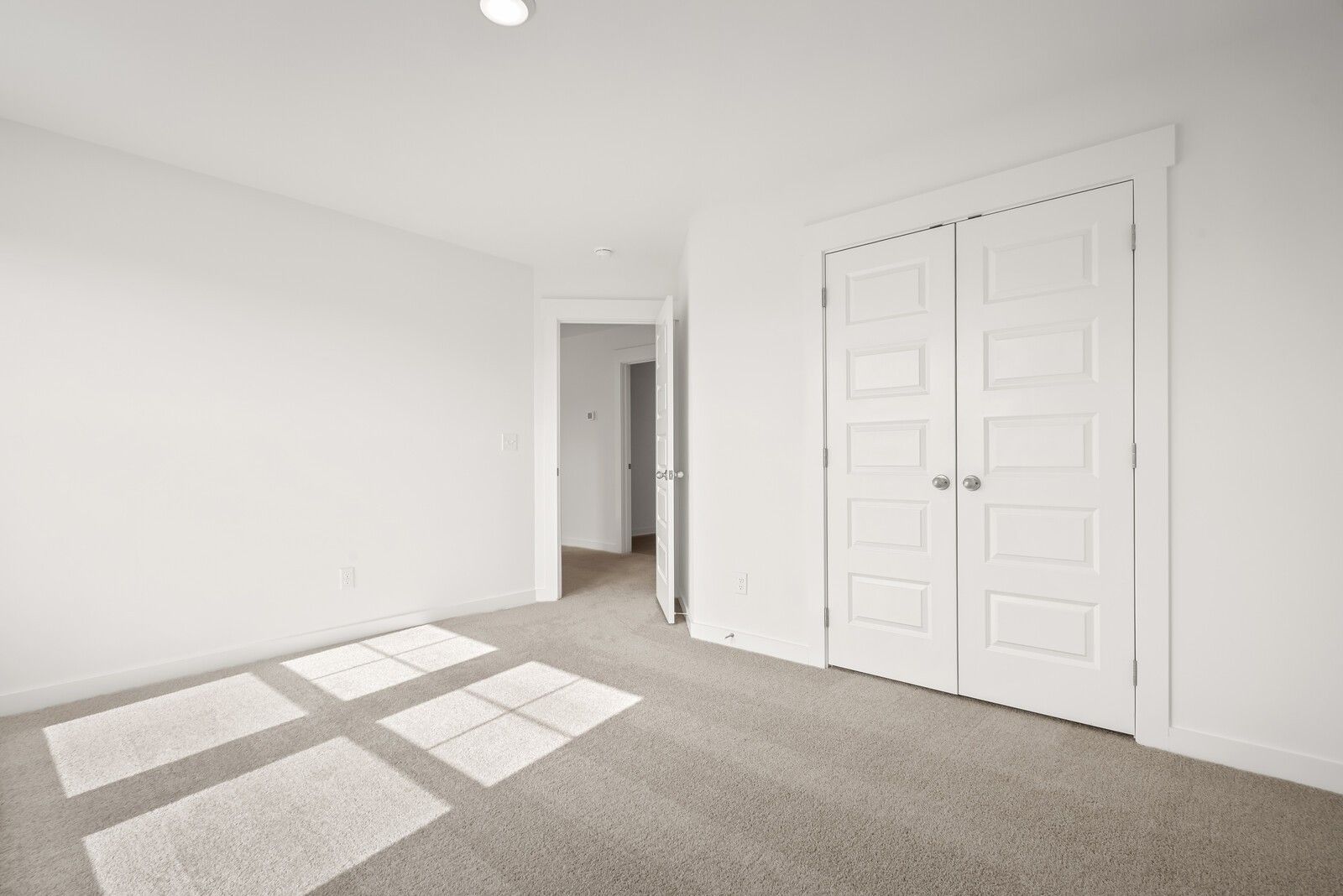 Spacious white bedroom with double closet doors, open ensuite doorway, and carpeted floor in Davidson Homes The Logan C, Gallatin, TN