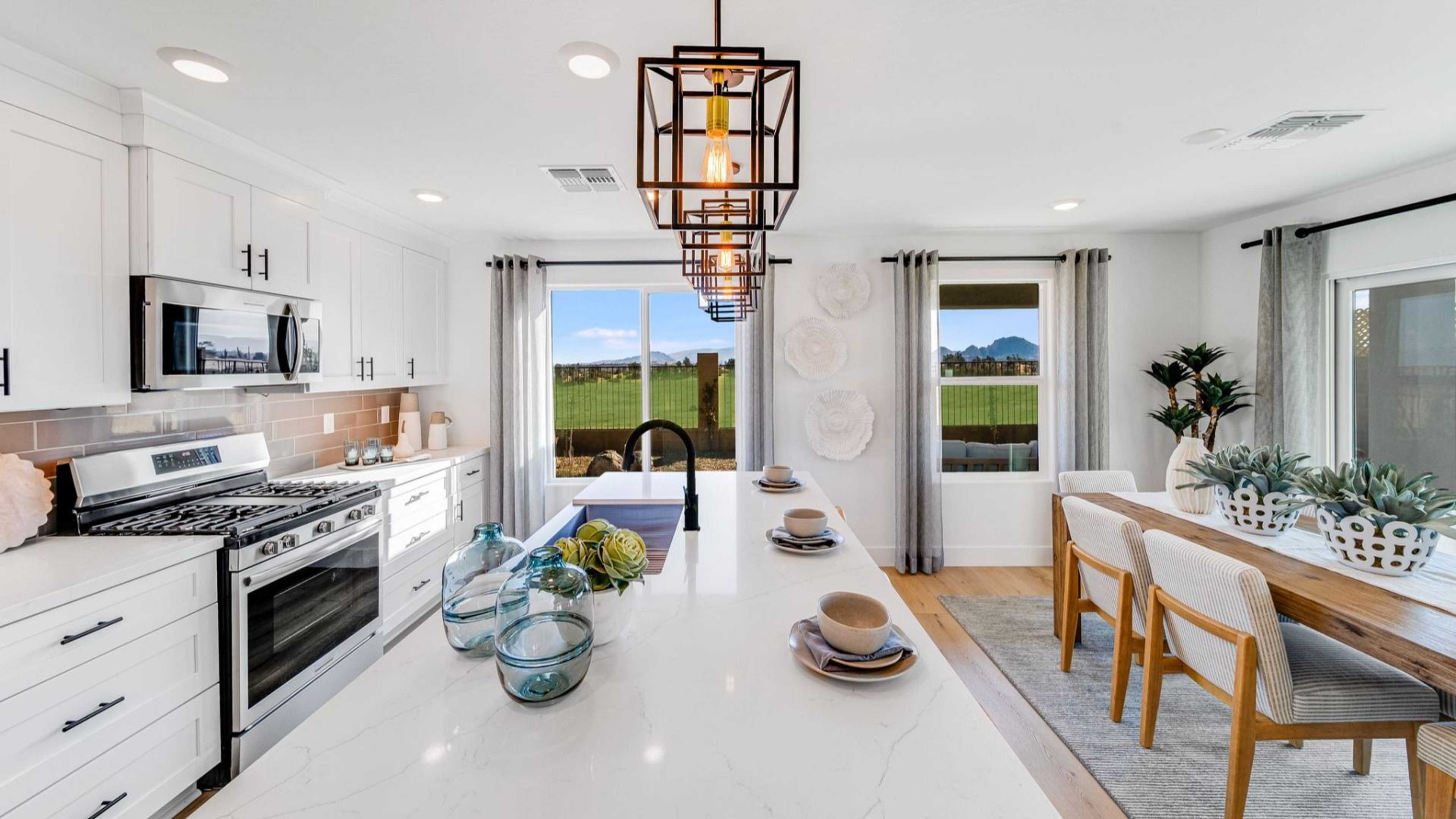Spacious modern kitchen in South Ranch Southern Collection Prescott AZ with white quartz island, stainless appliances, pendant lighting and desert views