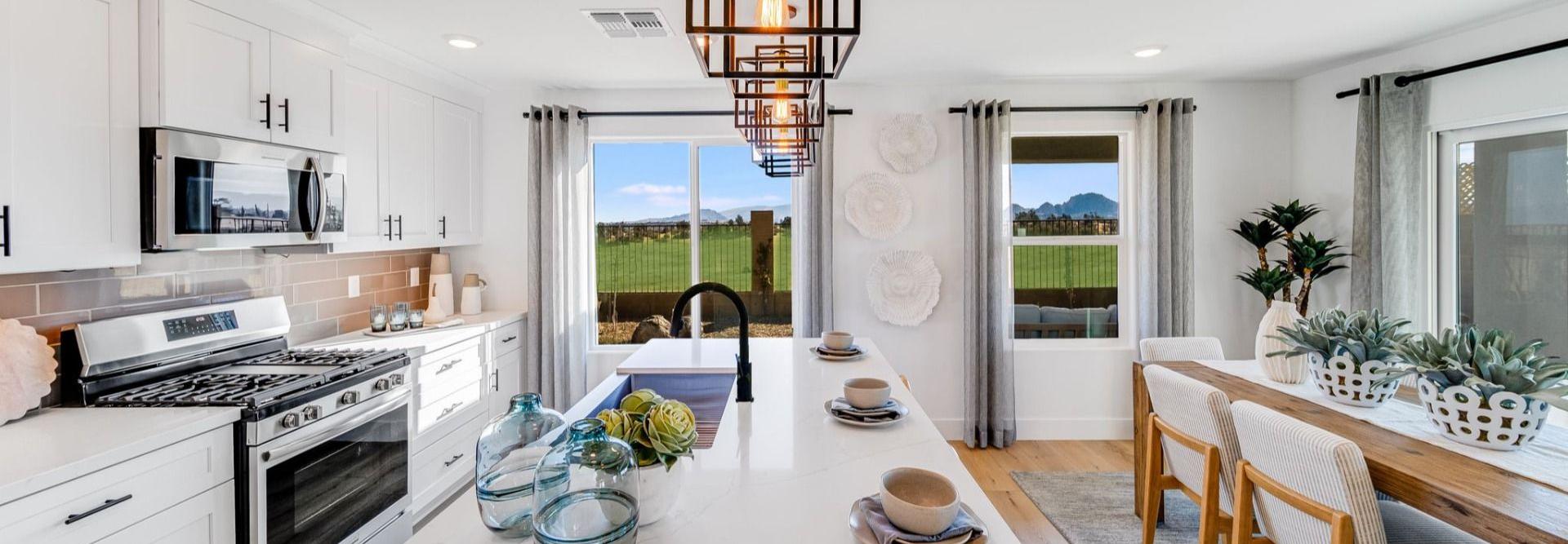 Spacious modern kitchen in South Ranch Southern Collection Prescott AZ with white quartz island, stainless appliances, pendant lighting and desert views