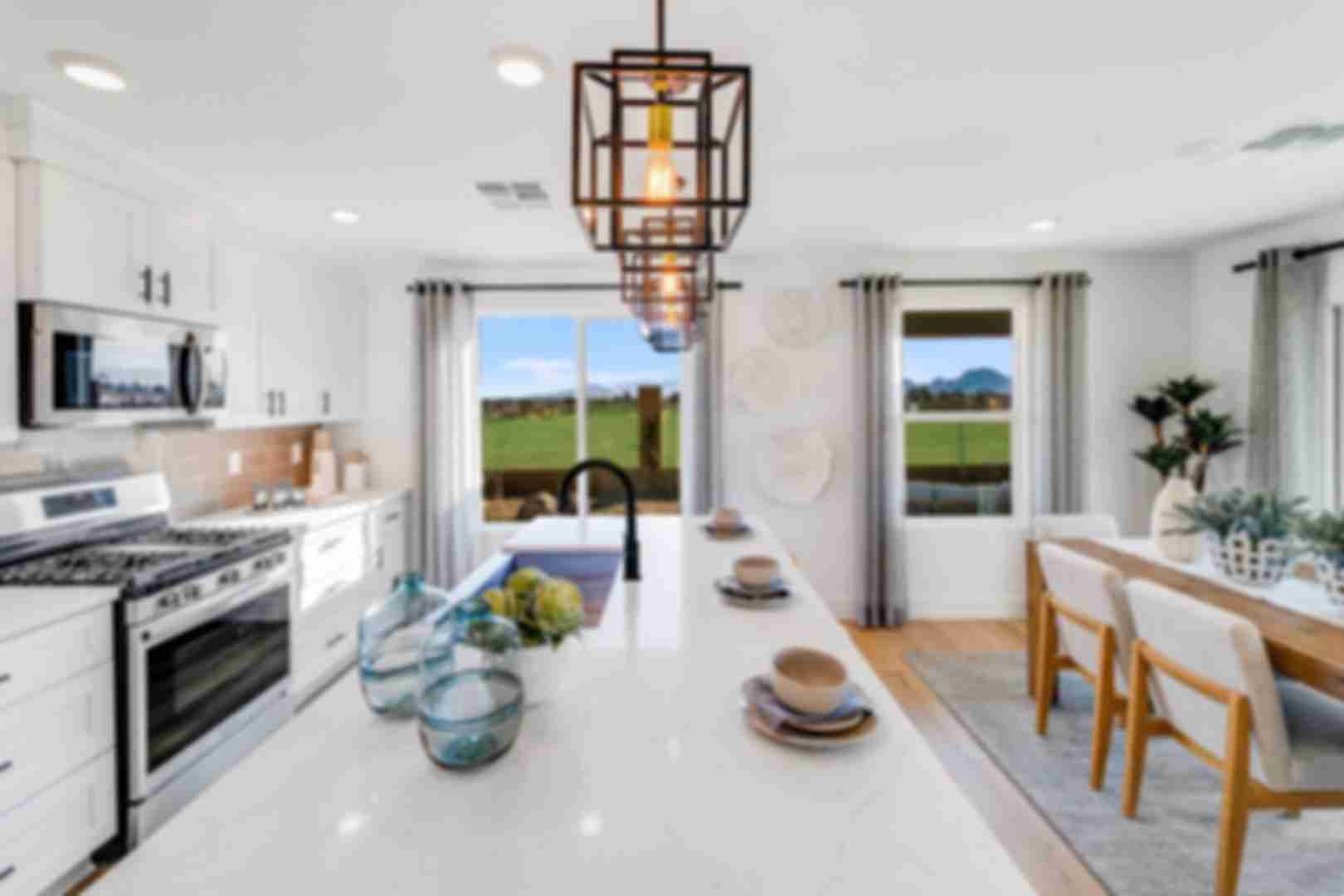 Spacious modern kitchen in South Ranch Southern Collection Prescott AZ with white quartz island, stainless appliances, pendant lighting and desert views