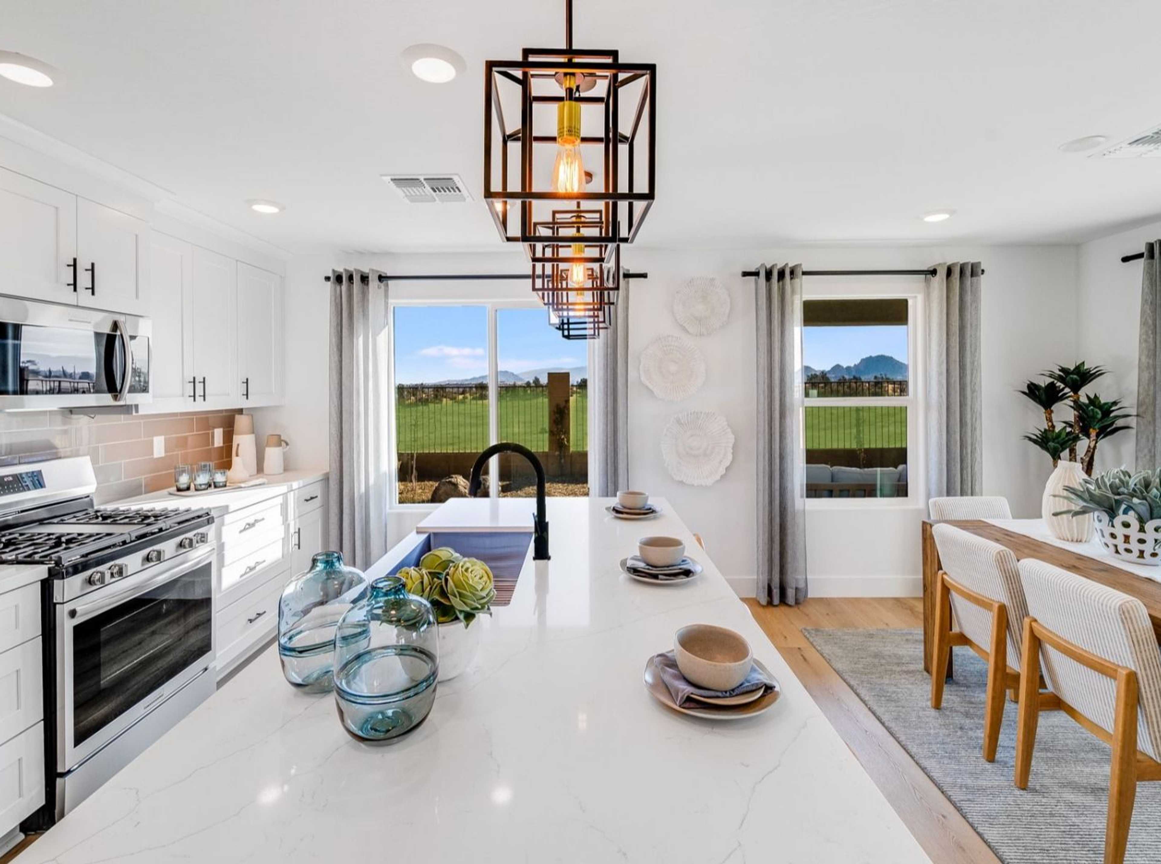 Spacious modern kitchen in South Ranch Southern Collection Prescott AZ with white quartz island, stainless appliances, pendant lighting and desert views