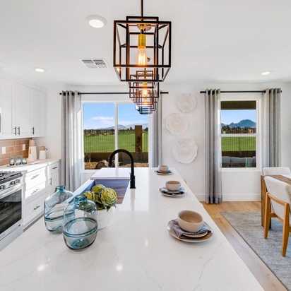 Spacious modern kitchen in South Ranch Southern Collection Prescott AZ with white quartz island, stainless appliances, pendant lighting and desert views