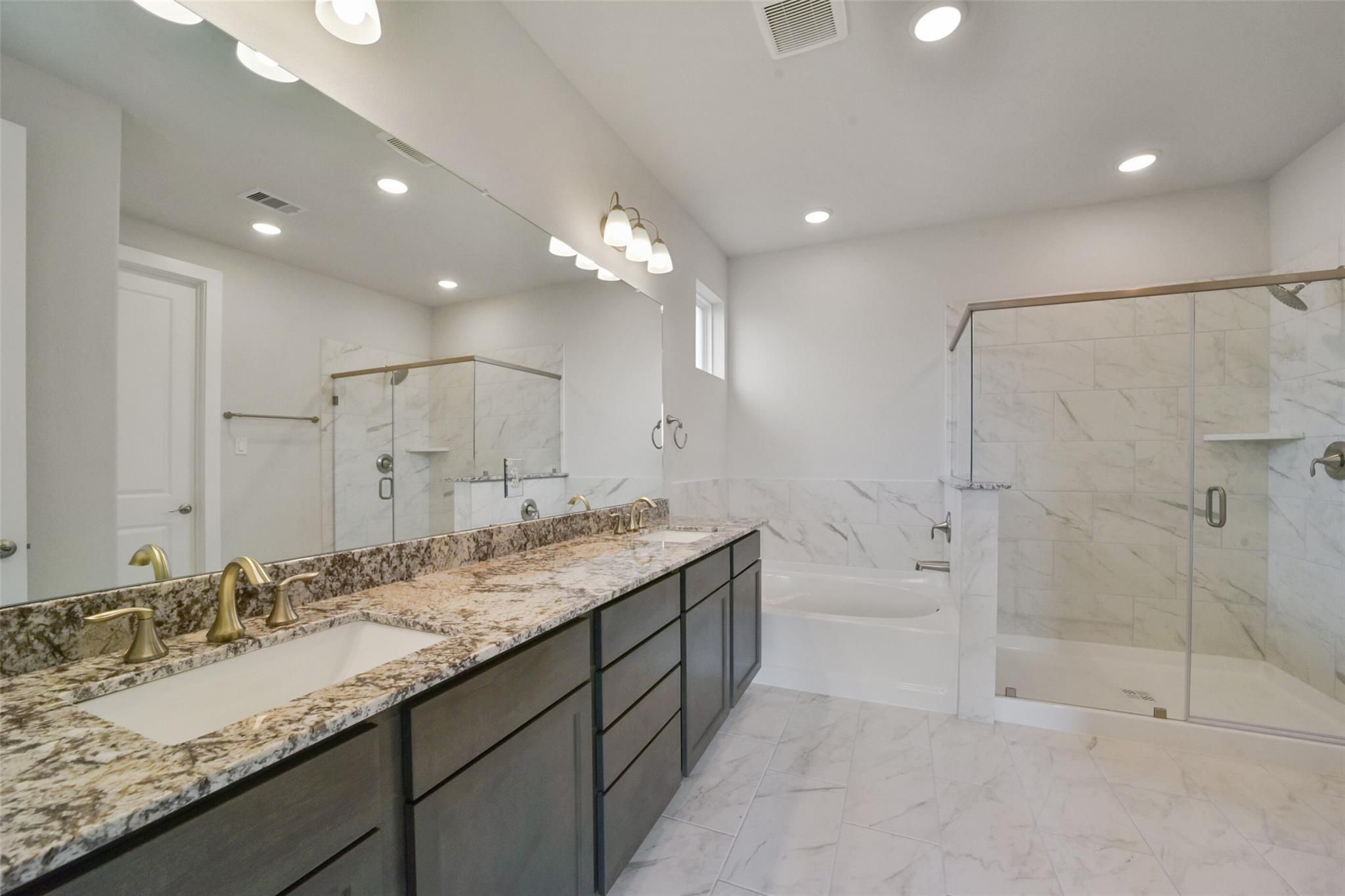Elegant master bathroom with double granite vanity, freestanding tub, and frameless glass shower in Davidson Homes Zion A, Lago Mar