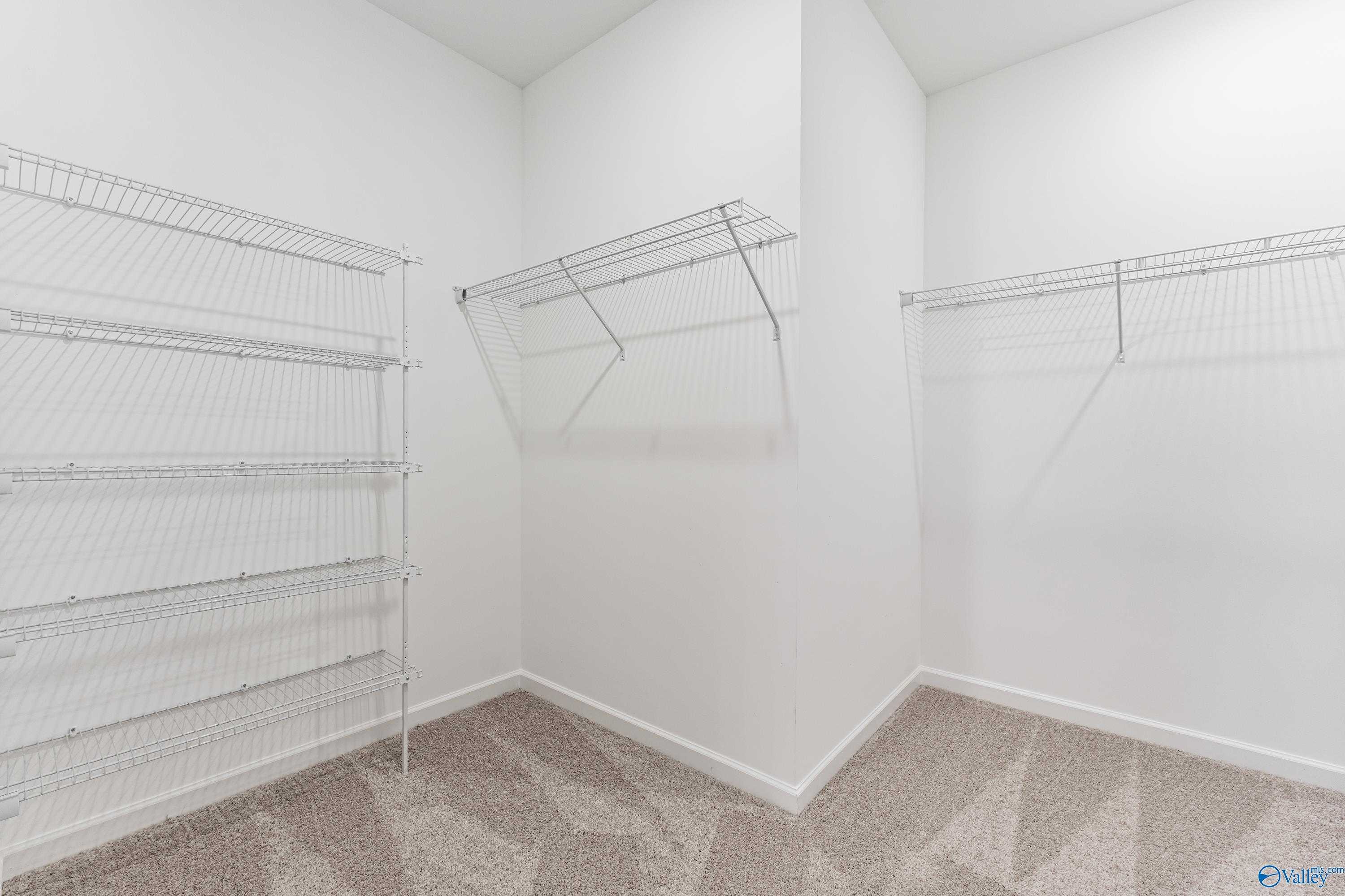 Spacious walk-in closet with wire shelving and hanging rods in Davidson Homes The Phoenix, Hazel Green, Alabama