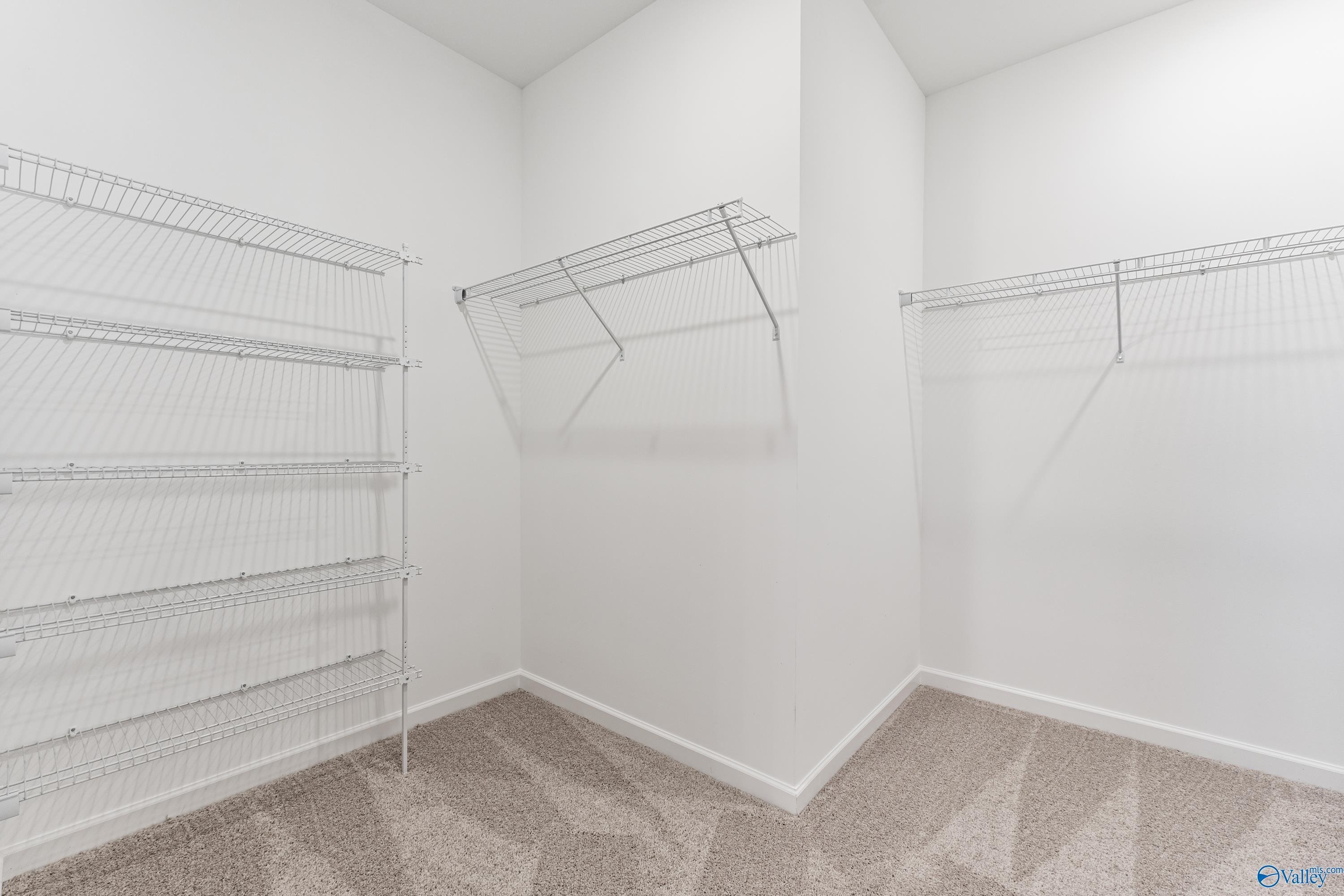Spacious walk-in closet with wire shelving and hanging rods in Davidson Homes The Phoenix, Hazel Green, Alabama