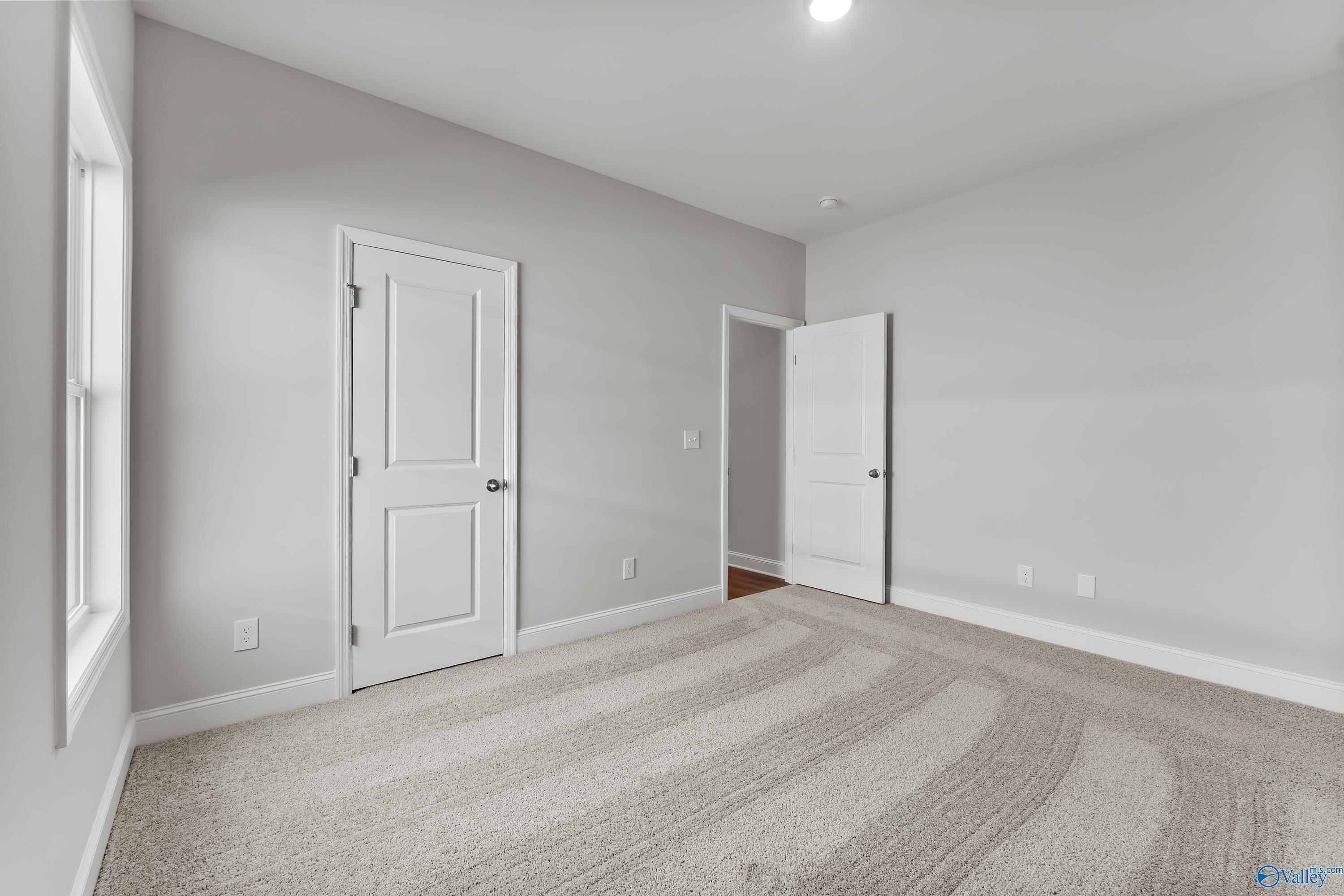 Spacious secondary bedroom with gray walls, white doors, carpet flooring in Davidson Homes The Daphne, Hazel Green, Alabama