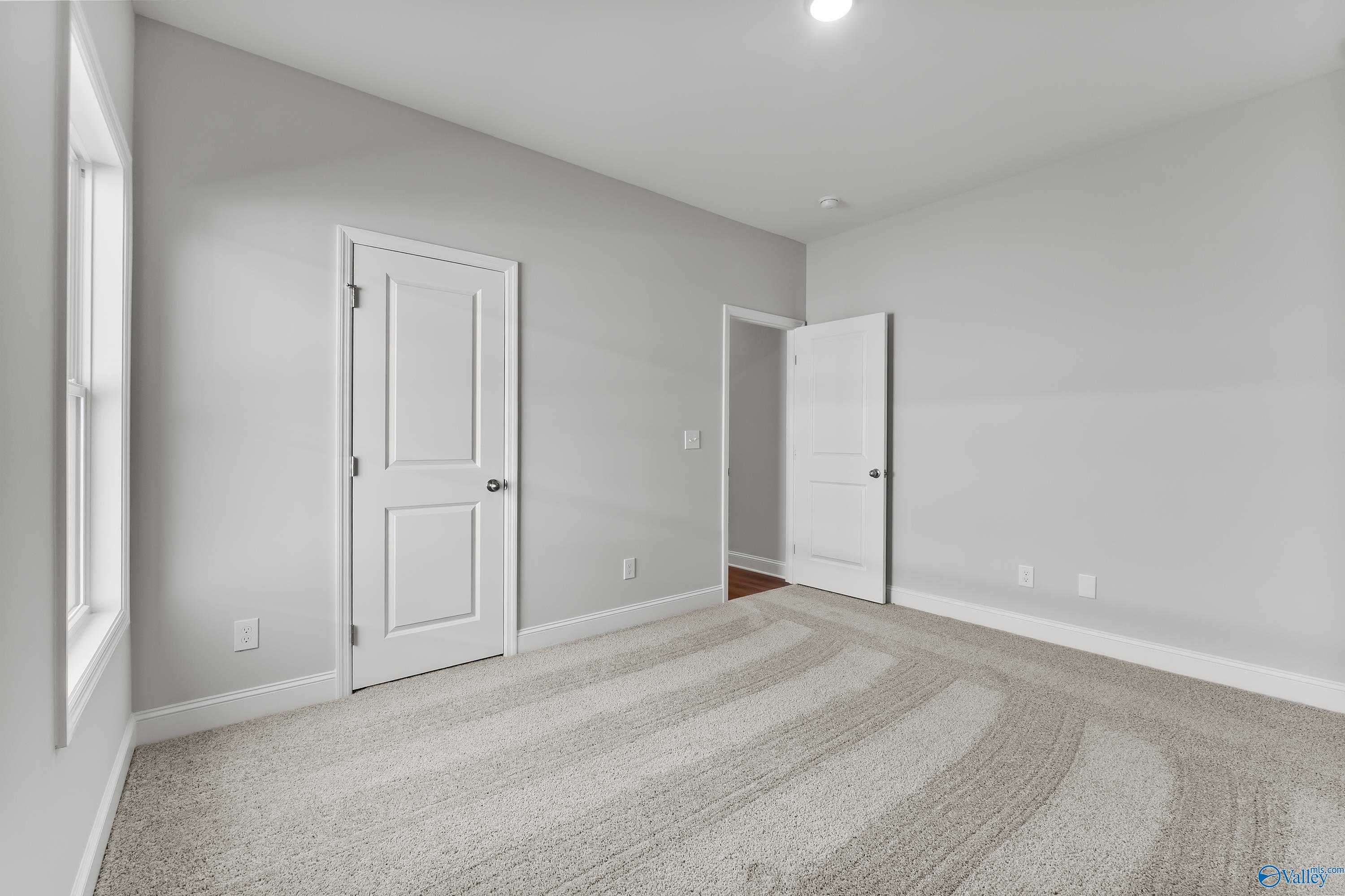 Spacious secondary bedroom with gray walls, white doors, carpet flooring in Davidson Homes The Daphne, Hazel Green, Alabama