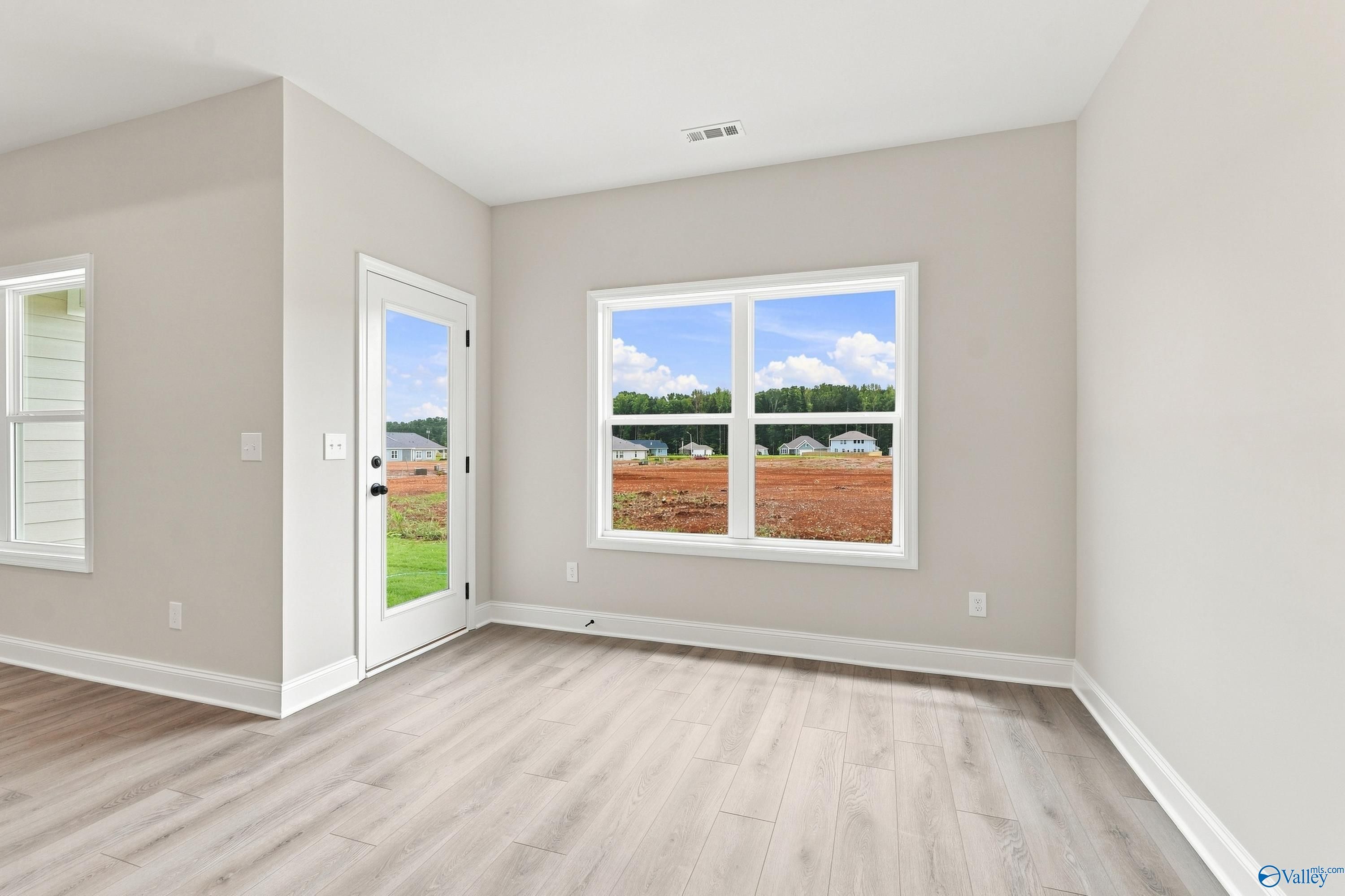 Bright living area with wood-look flooring and backyard views in The Asheville E floor plan, Forest Glen, Hazel Green, AL.