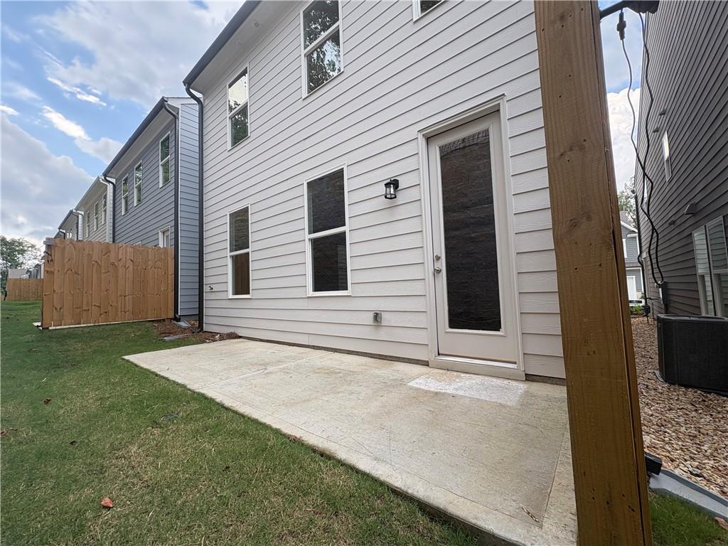 Back view of The Marion B two-story home with concrete patio, sliding glass door, and fenced backyard in The Village at Shallowford, Kennesaw, Georgia