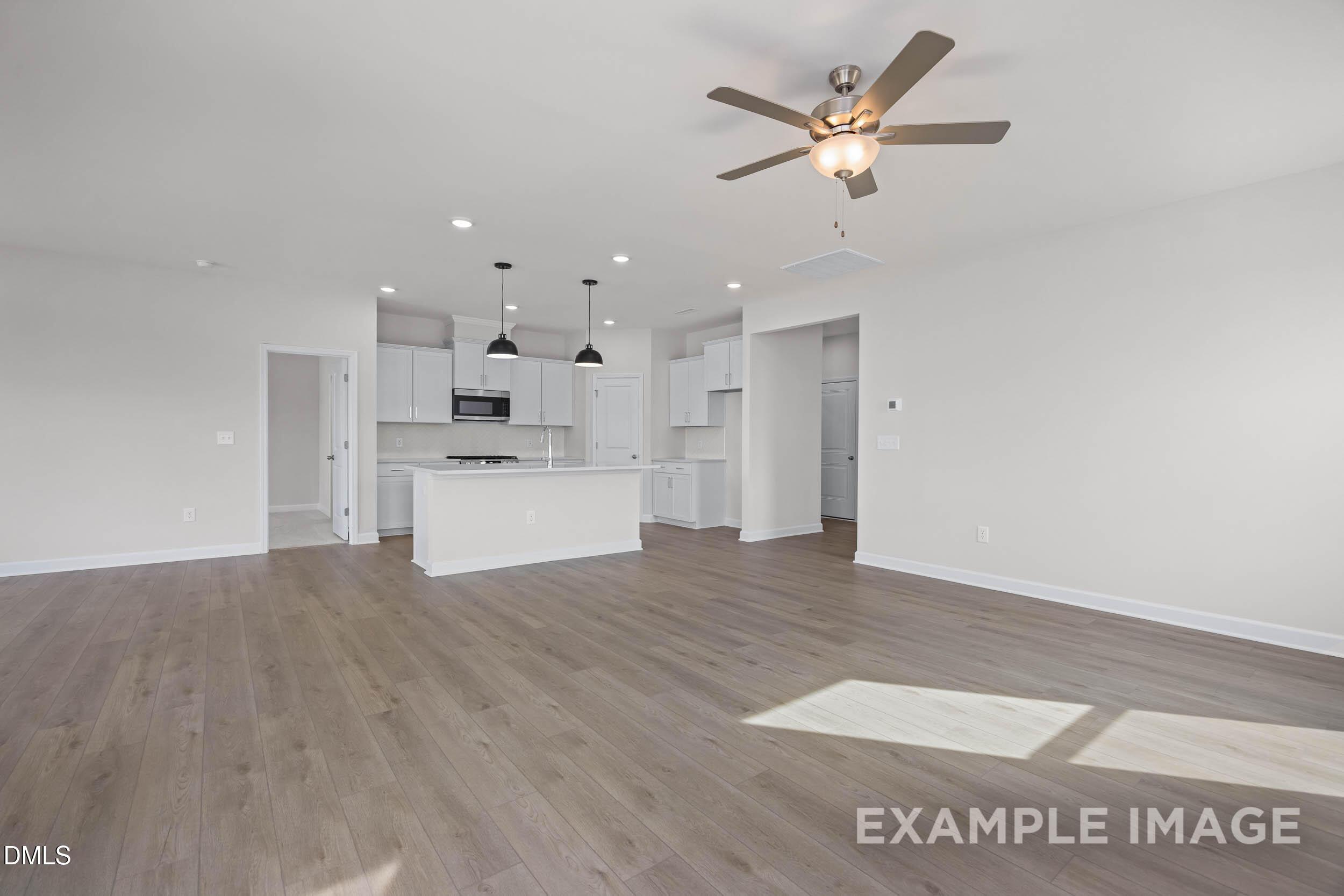 Open-concept living room and kitchen with white cabinetry in The Franklin C floor plan at Retreat at North Main, Lillington.