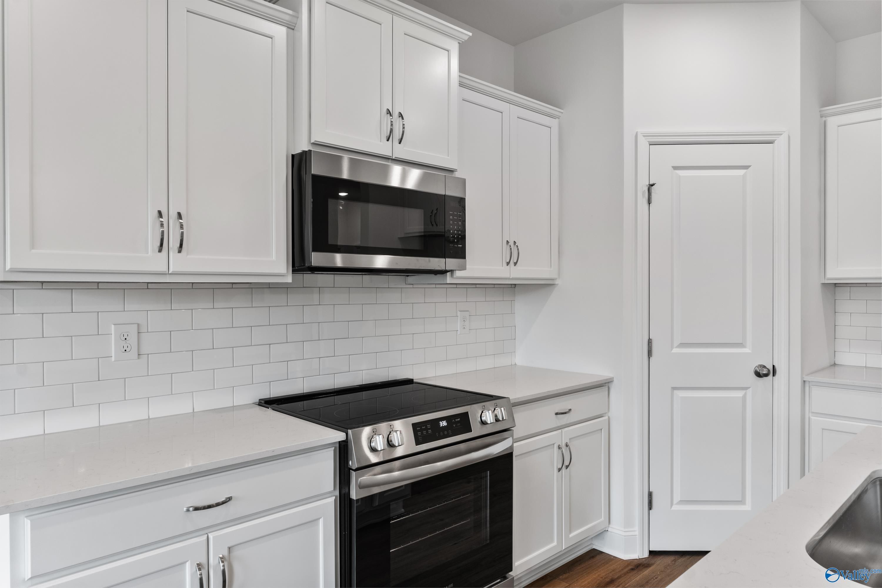 Modern white kitchen with stainless steel appliances, subway tile backsplash in Davidson Homes The Asheville C, New Market, AL