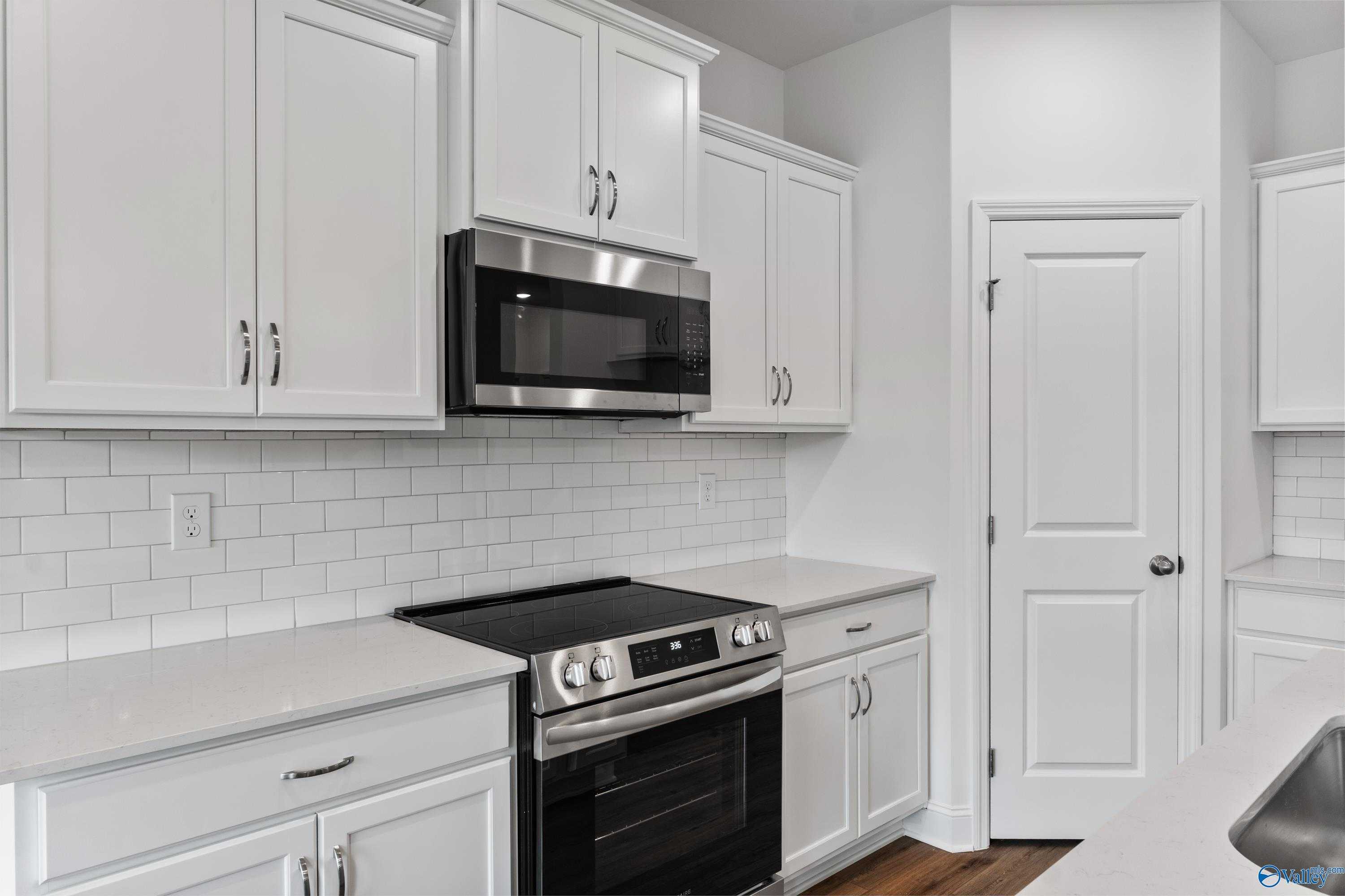 Modern white kitchen with stainless steel appliances, subway tile backsplash in Davidson Homes The Asheville C, New Market, AL