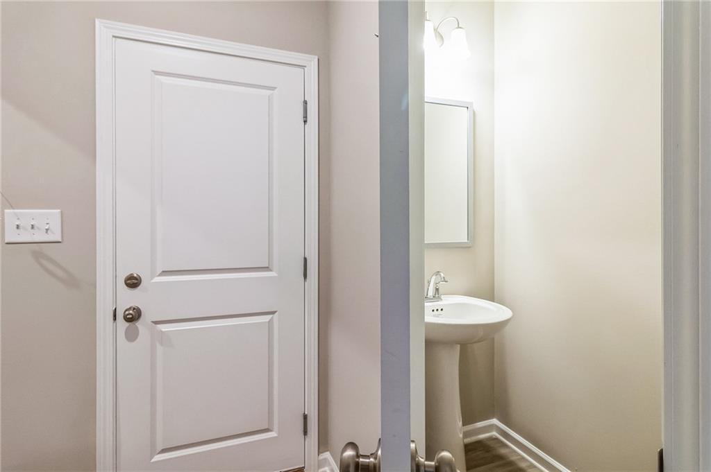 Elegant powder room with pedestal sink, mirror, and soft lighting in Evermore Homes The Stella, Ivy Glen, Perry, Georgia