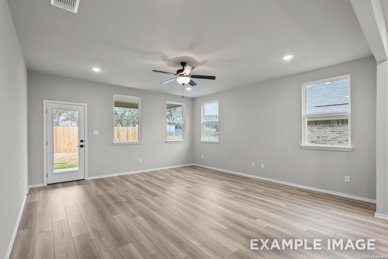 Spacious, light-filled living area with wood-look flooring in The Glenwood E floor plan at Royal Crest, San Antonio.