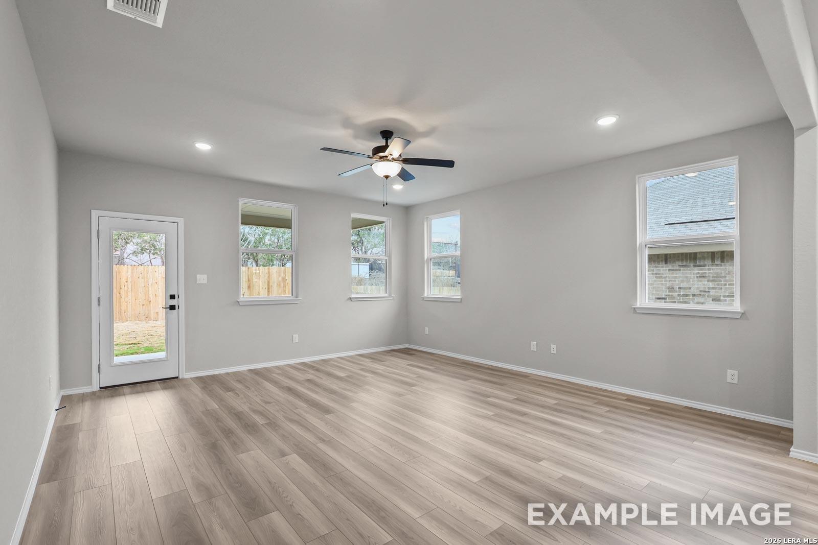 Spacious, light-filled living area with wood-look flooring in The Glenwood E floor plan at Royal Crest, San Antonio.