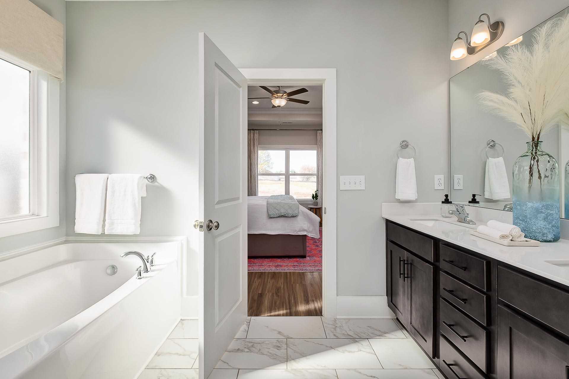 Spacious master bathroom at Newby Chapel in Athens Alabama with freestanding tub, double vanity, and bedroom view