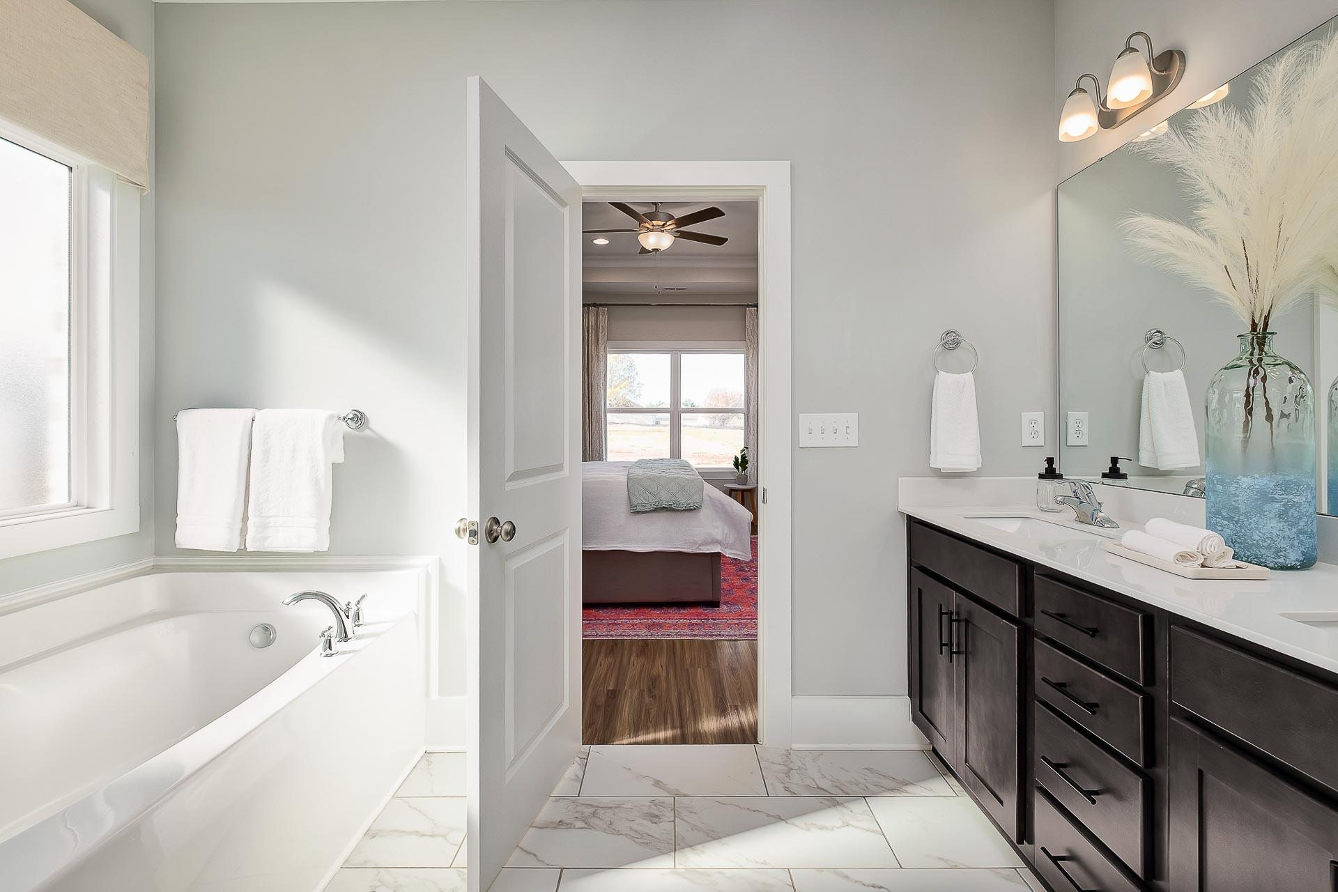 Spacious master bathroom at Newby Chapel in Athens Alabama with freestanding tub, double vanity, and bedroom view