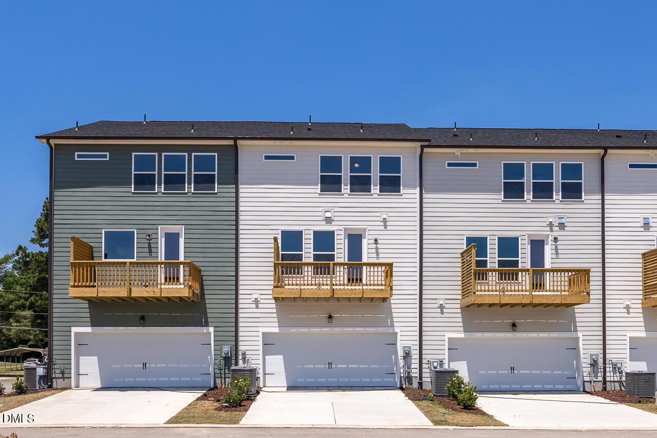 3-story townhome exterior with 2-car garages and wooden balconies at The Mitchell floor plan in Camden Park, Knightdale, NC.
