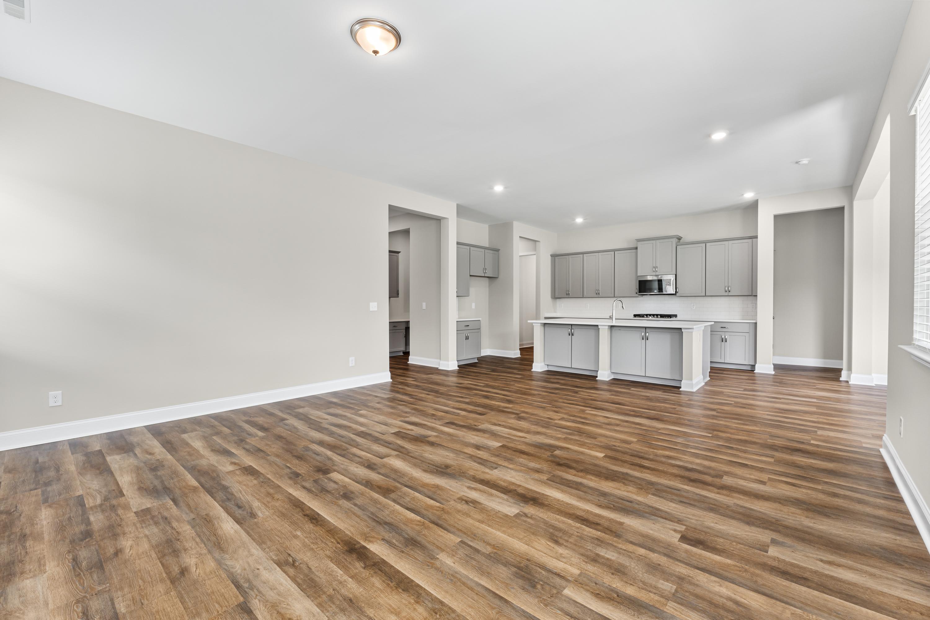 Spacious open kitchen in The Arcadia B with white cabinets, large center island, hardwood floors
