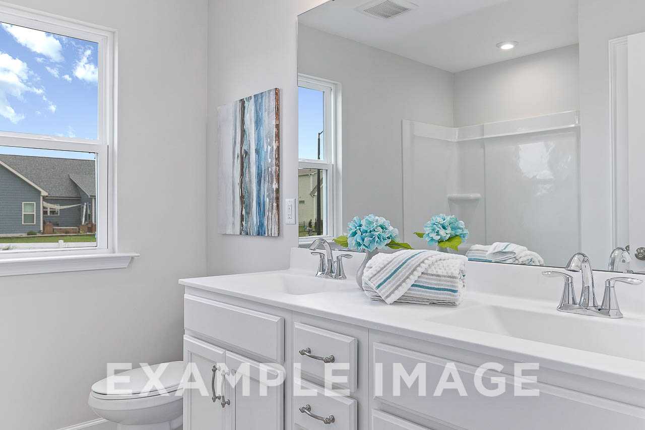 Spacious master bathroom in The Willow C featuring white double vanity, chrome faucets, blue hydrangeas, and walk-in shower