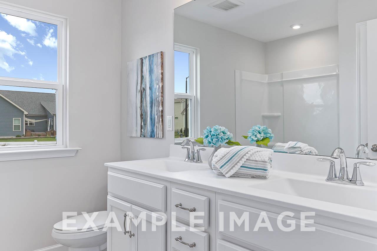Spacious master bathroom in The Willow C featuring white double vanity, chrome faucets, blue hydrangeas, and walk-in shower
