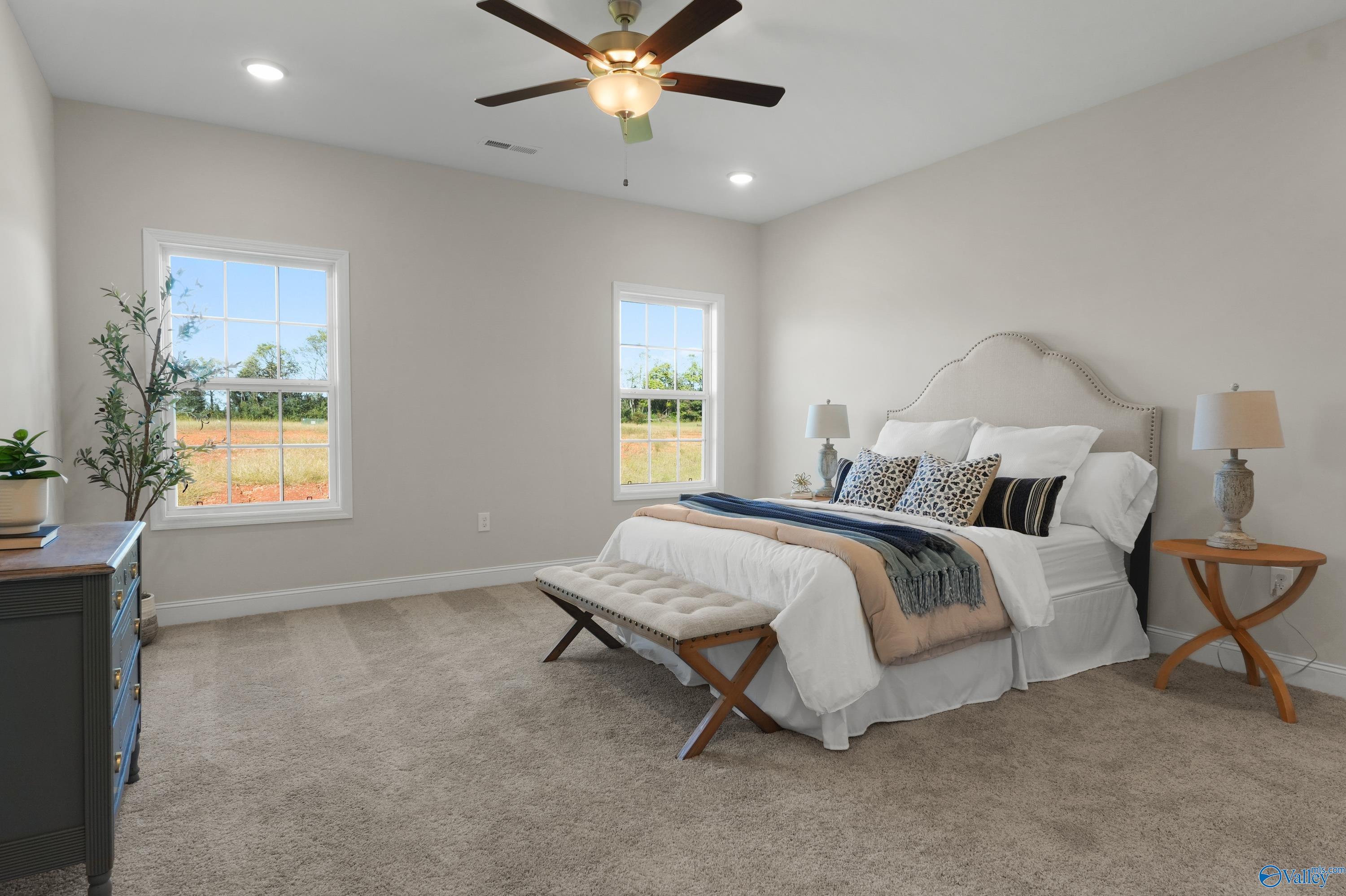 Spacious master bedroom with king bed, large windows overlooking fields, ceiling fan in Davidson Homes The Rockford B, Toney, Alabama