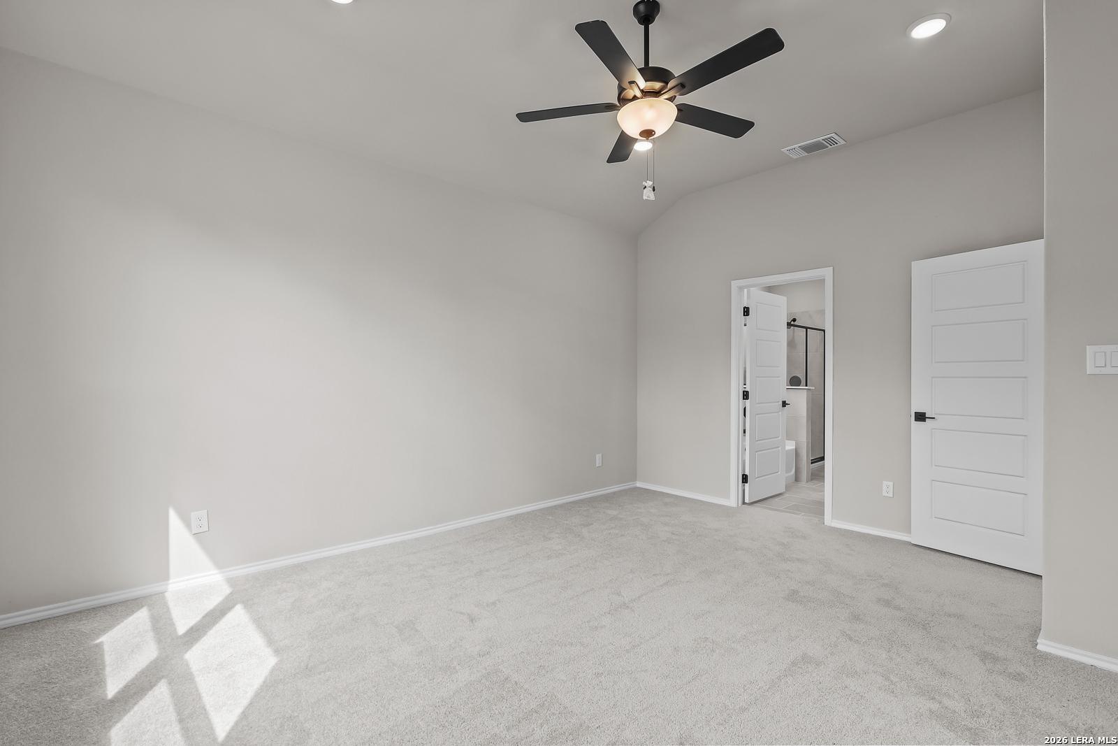 Spacious carpeted bedroom with ceiling fan and en suite bath access in Davidson Homes Sequoia C plan, Royal Crest, San Antonio