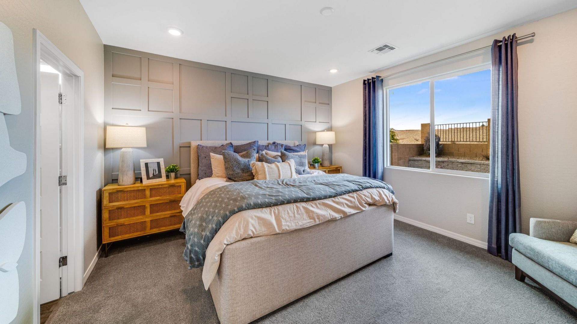 Spacious primary bedroom at Vineyards at Cottonwood in Cottonwood AZ with king bed, blue bedding, gray shiplap wall, and desert view window