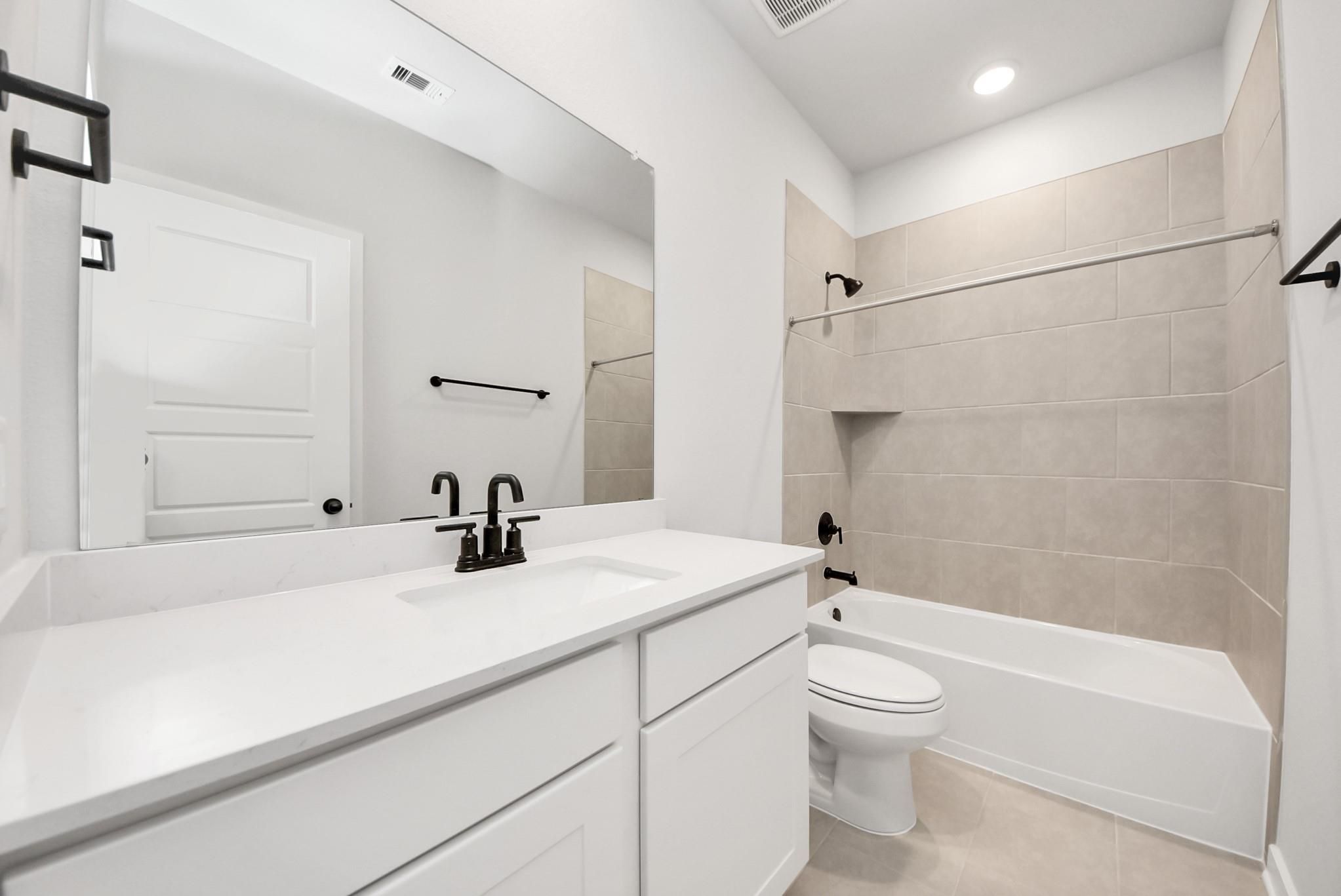 Modern bathroom with white vanity, matte black fixtures, and tiled tub-shower in The Daphne F plan, Sundance Cove, Crosby.