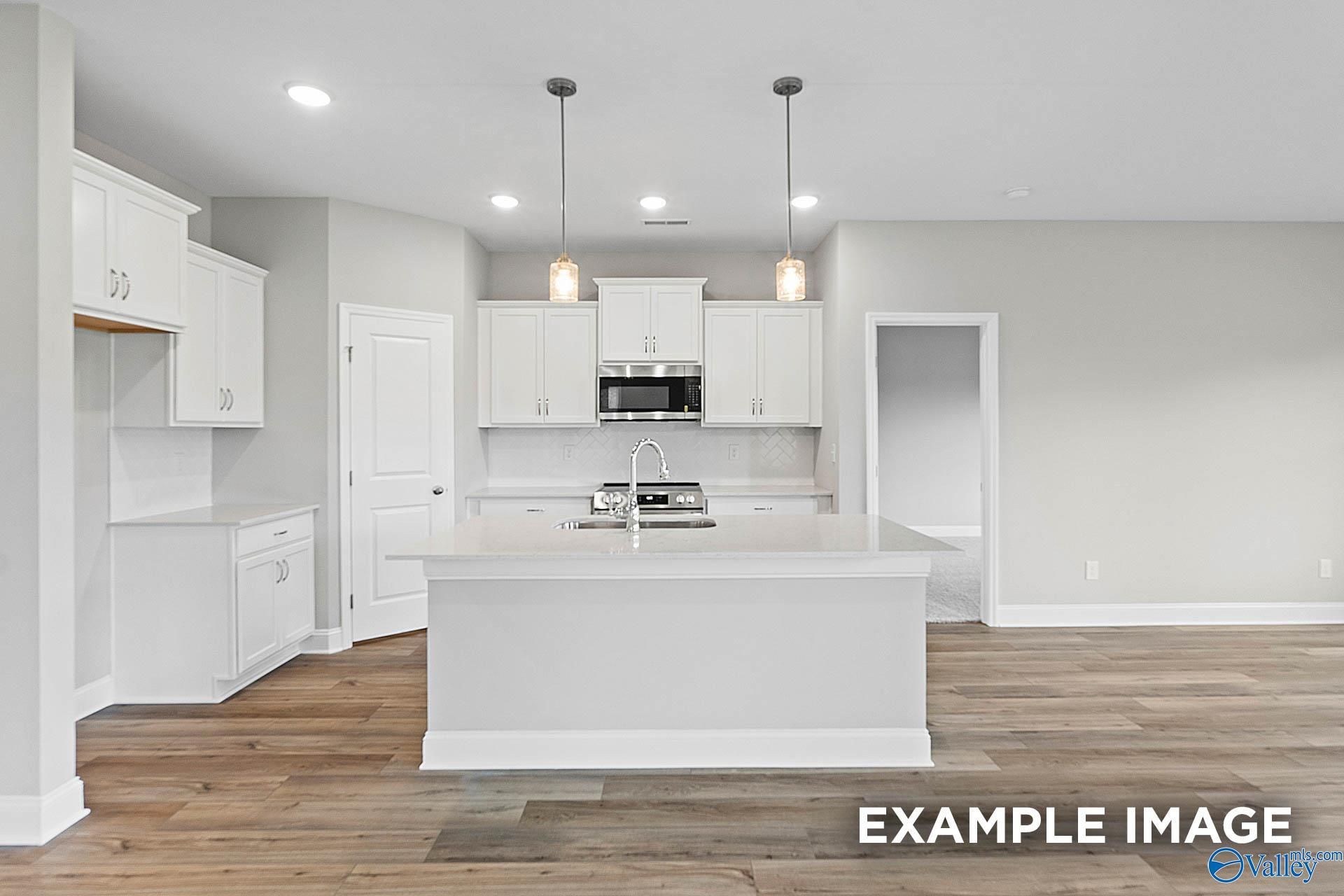 Bright white kitchen with island, stainless appliances, hardwood floors in Davidson Homes The Franklin E, Hazel Green, AL
