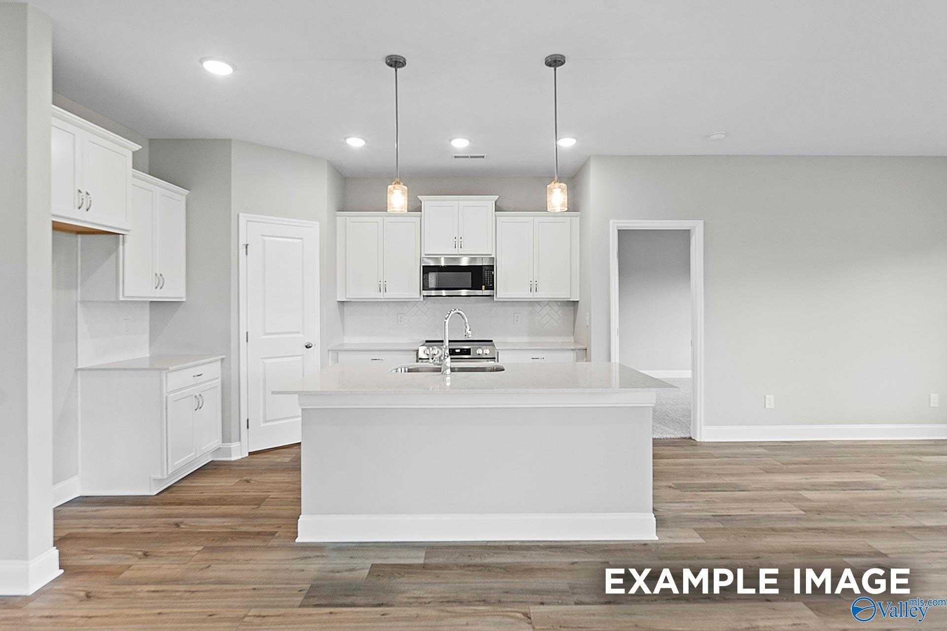 Bright white kitchen with island, stainless appliances, hardwood floors in Davidson Homes The Franklin E, Hazel Green, AL