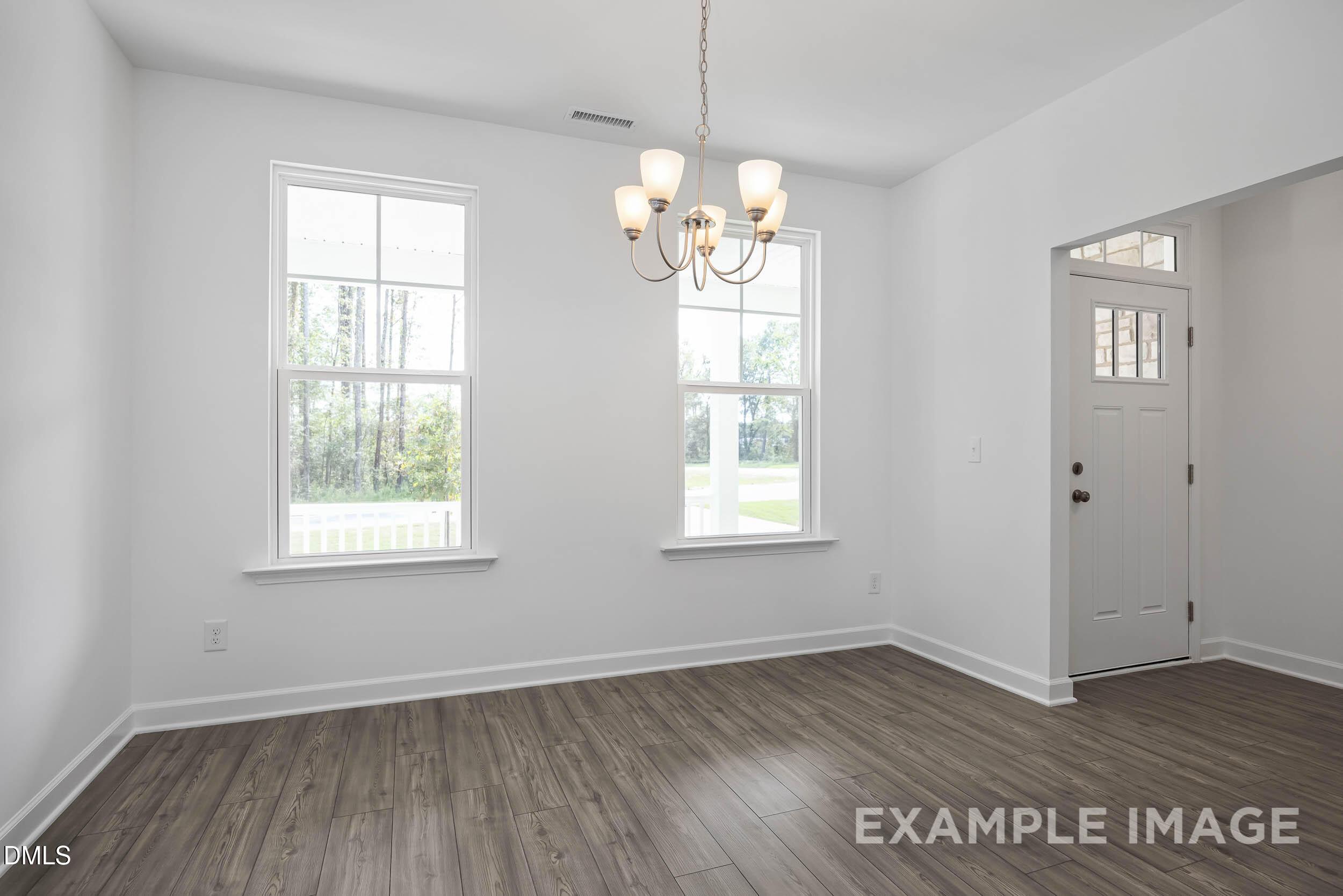 Bright dining room with brass chandelier, large windows overlooking porch, and hardwood floors in Davidson Homes The Willow D, Zebulon, NC