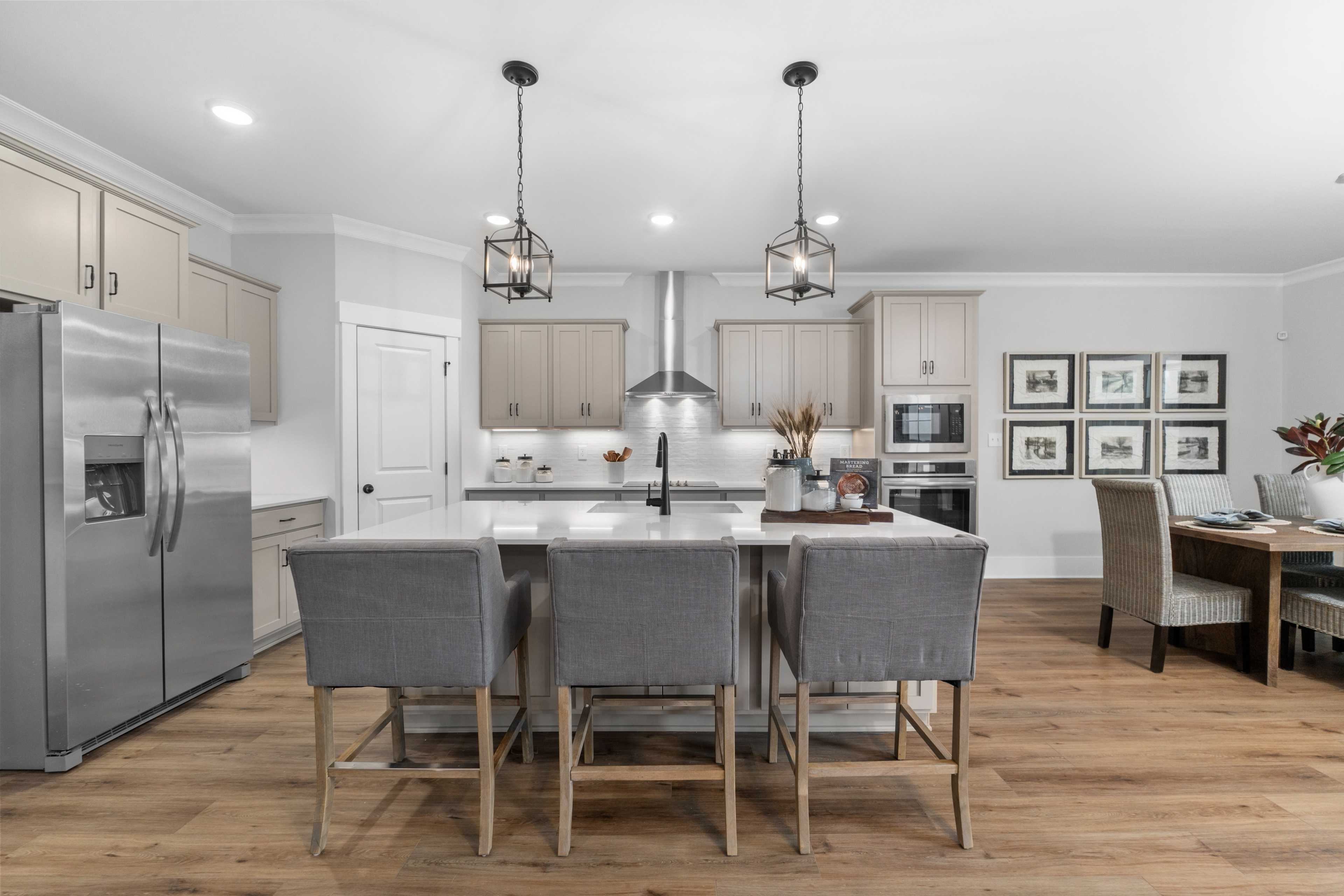 Spacious modern kitchen at Kendall Farms in Toney AL with white cabinets, stainless steel appliances, island sink and pendant lights