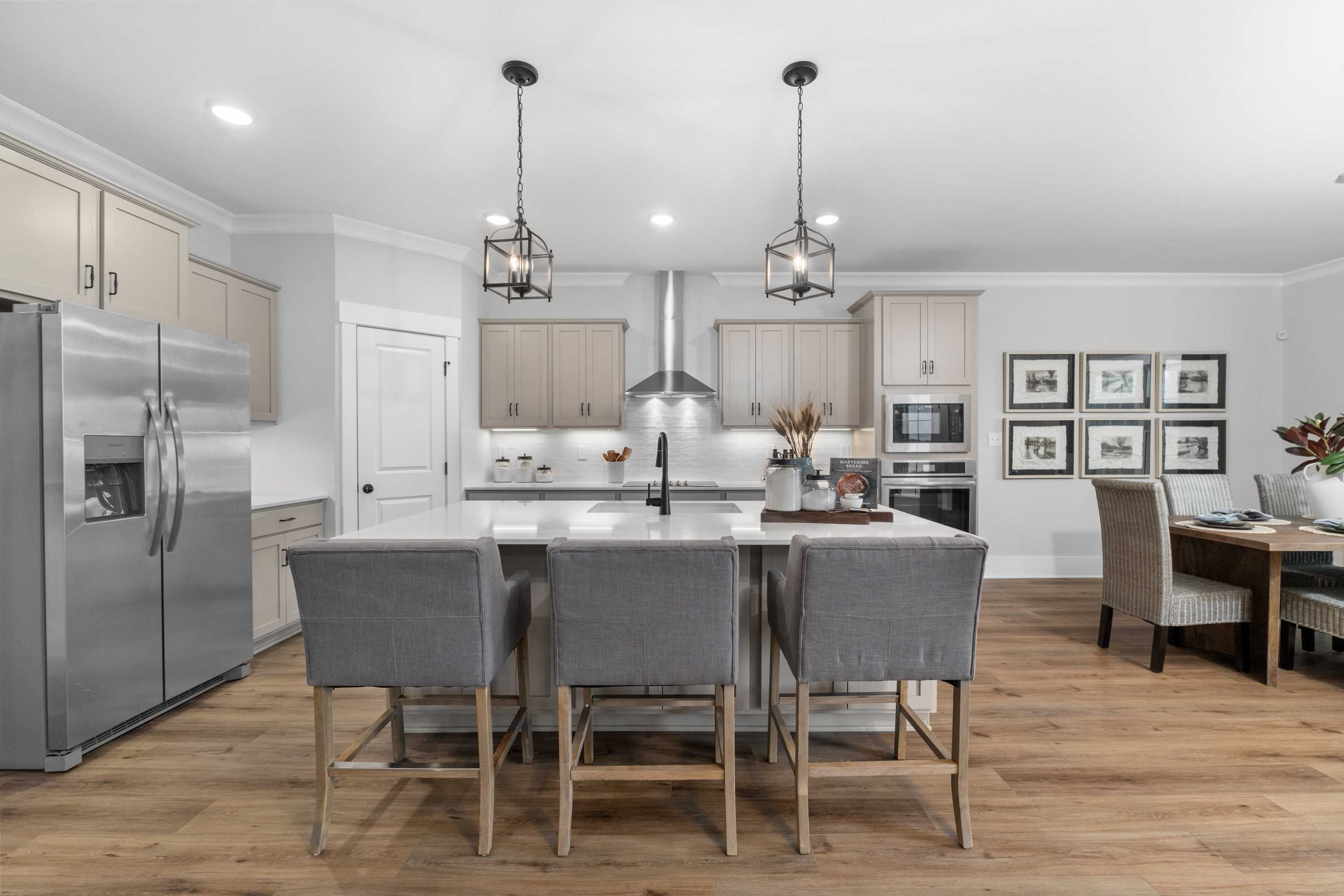 Spacious modern kitchen at Kendall Farms in Toney AL with white cabinets, stainless steel appliances, island sink and pendant lights