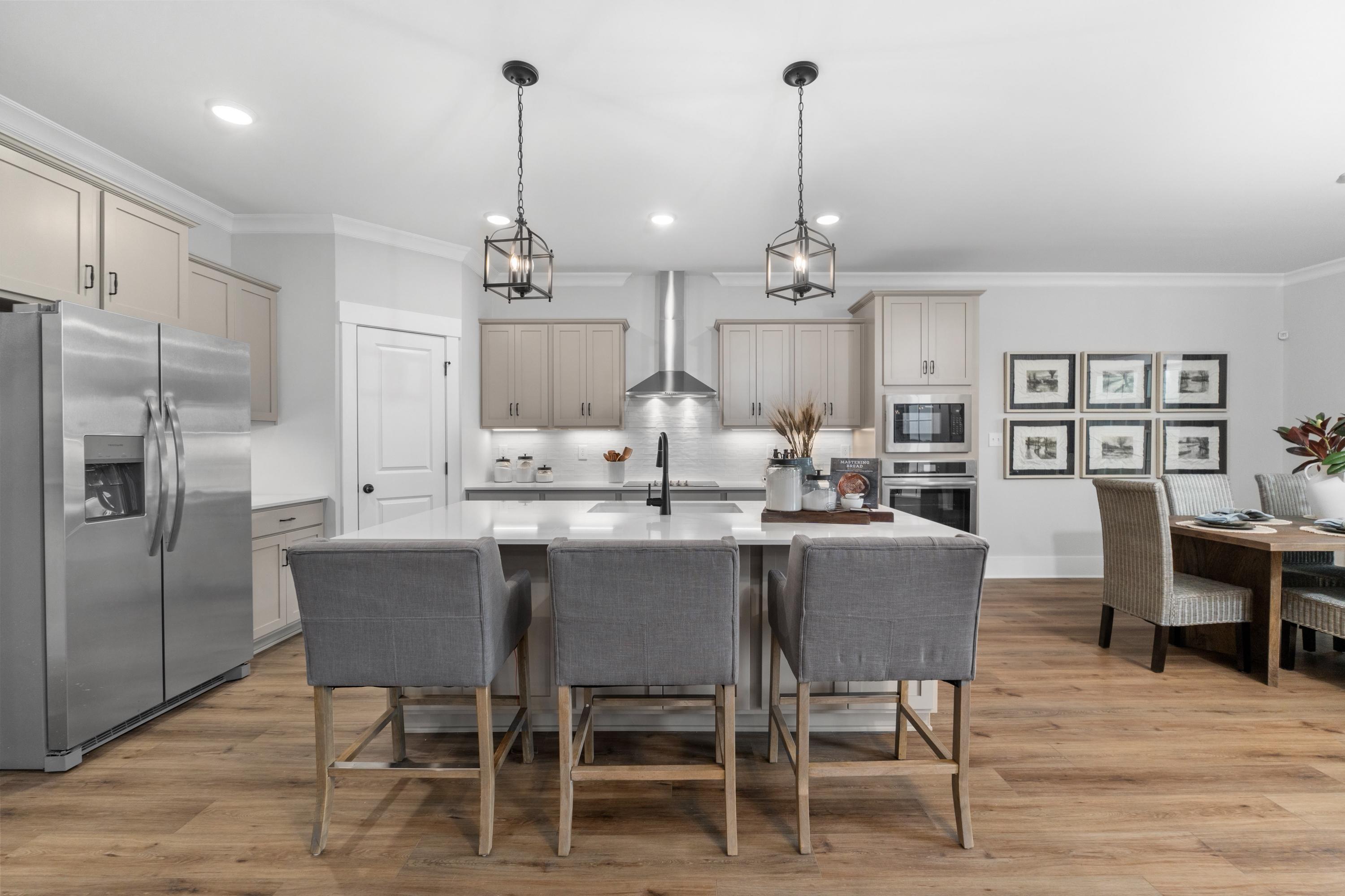 Spacious modern kitchen at Kendall Farms in Toney AL with white cabinets, stainless steel appliances, island sink and pendant lights
