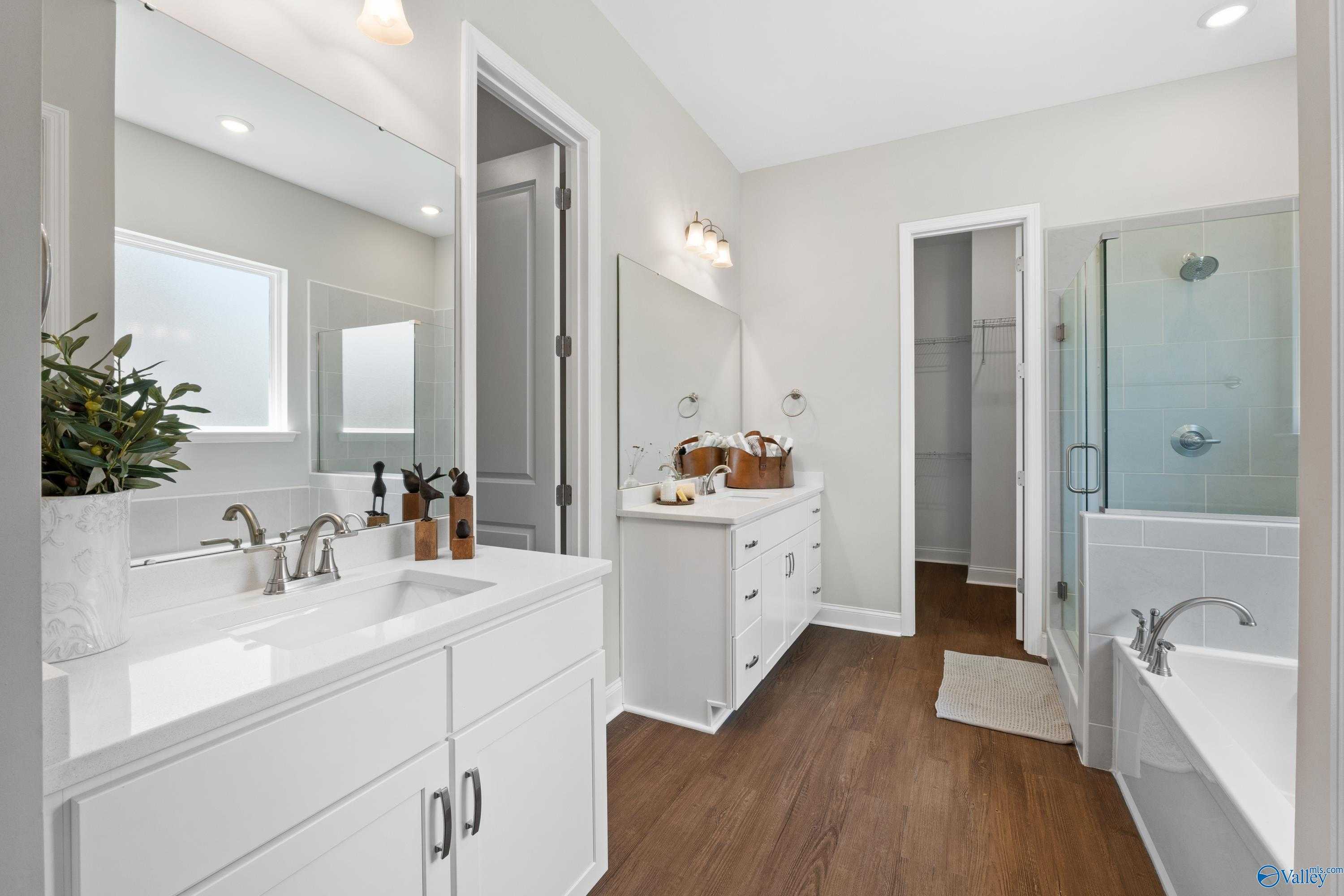 Elegant master bathroom with double white vanity, glass shower enclosure, and freestanding tub in Evermore Homes The Haven, Owens Cross Roads, Alabama