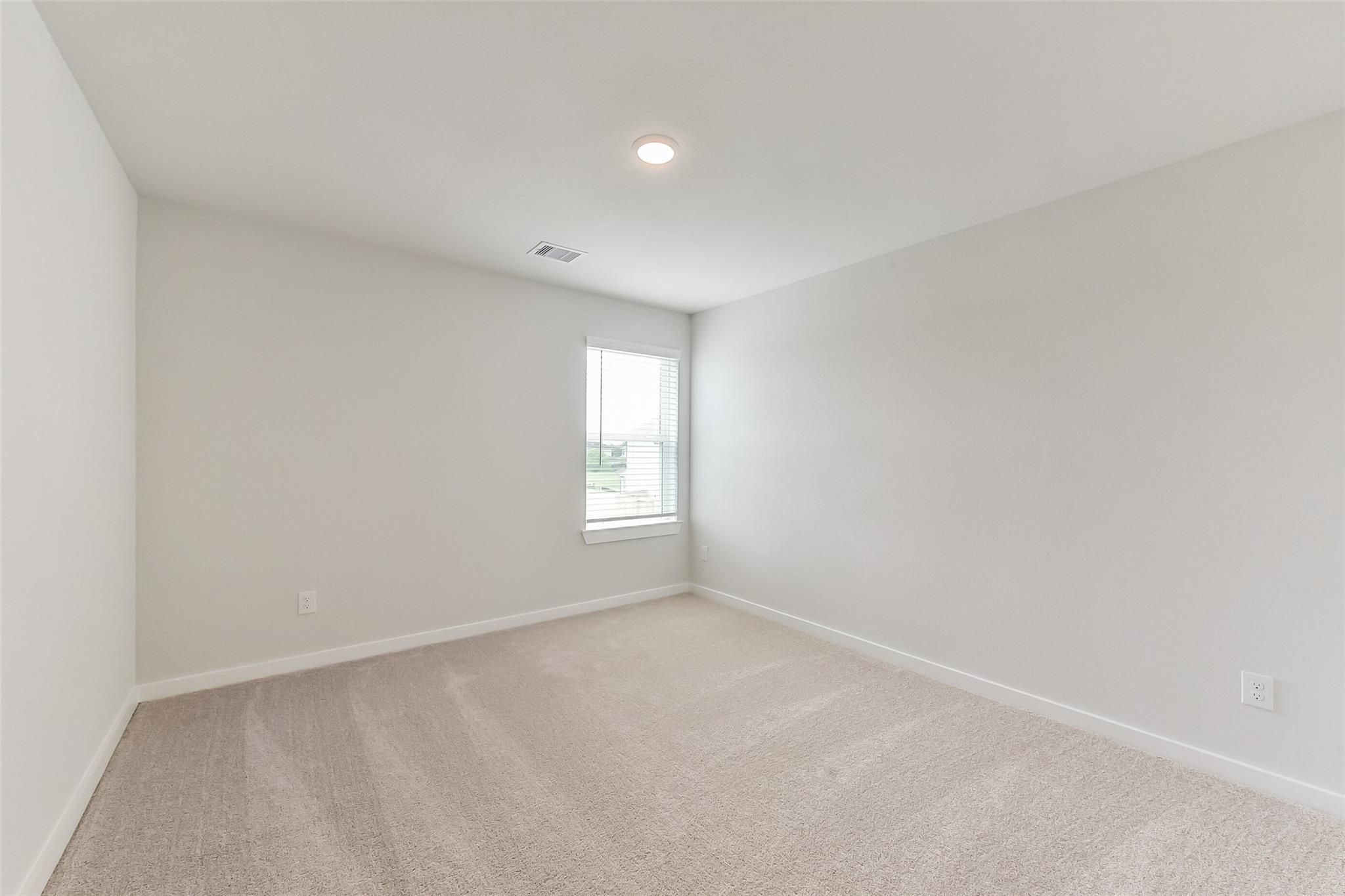Spacious empty bedroom with light gray walls, beige carpet, and window blinds in 5-bedroom Sabine F home, Dayton, Texas