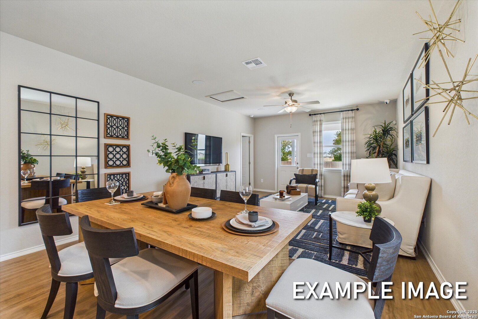 Modern dining room with wooden table, white chairs, plants, and TV in The Sabine C by Davidson Homes, Agave, San Antonio