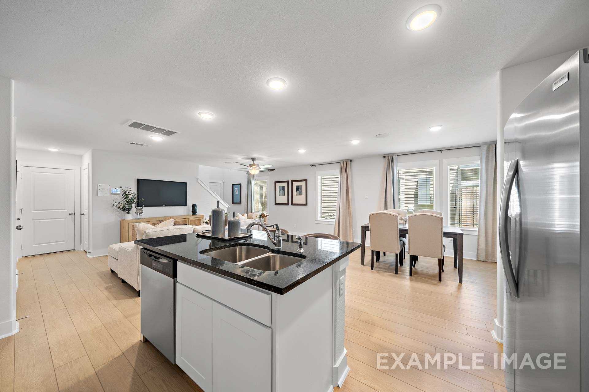 Spacious open-concept kitchen in The Rose B with granite island, stainless appliances, dining area, and living room by Davidson Homes