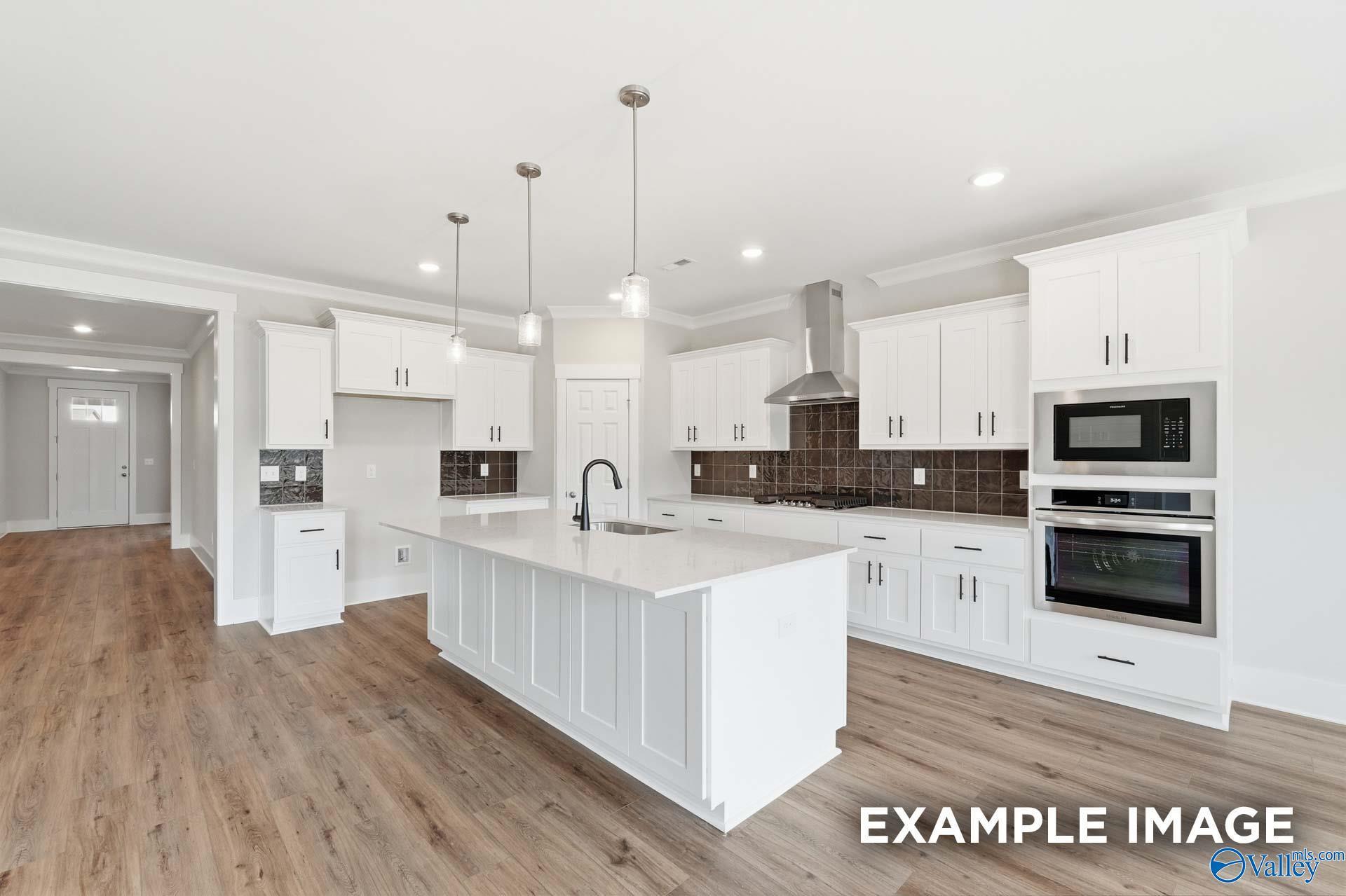 Modern kitchen with white cabinets, island, and stainless appliances in The Harrison floor plan, Briercreek, Meridianville.