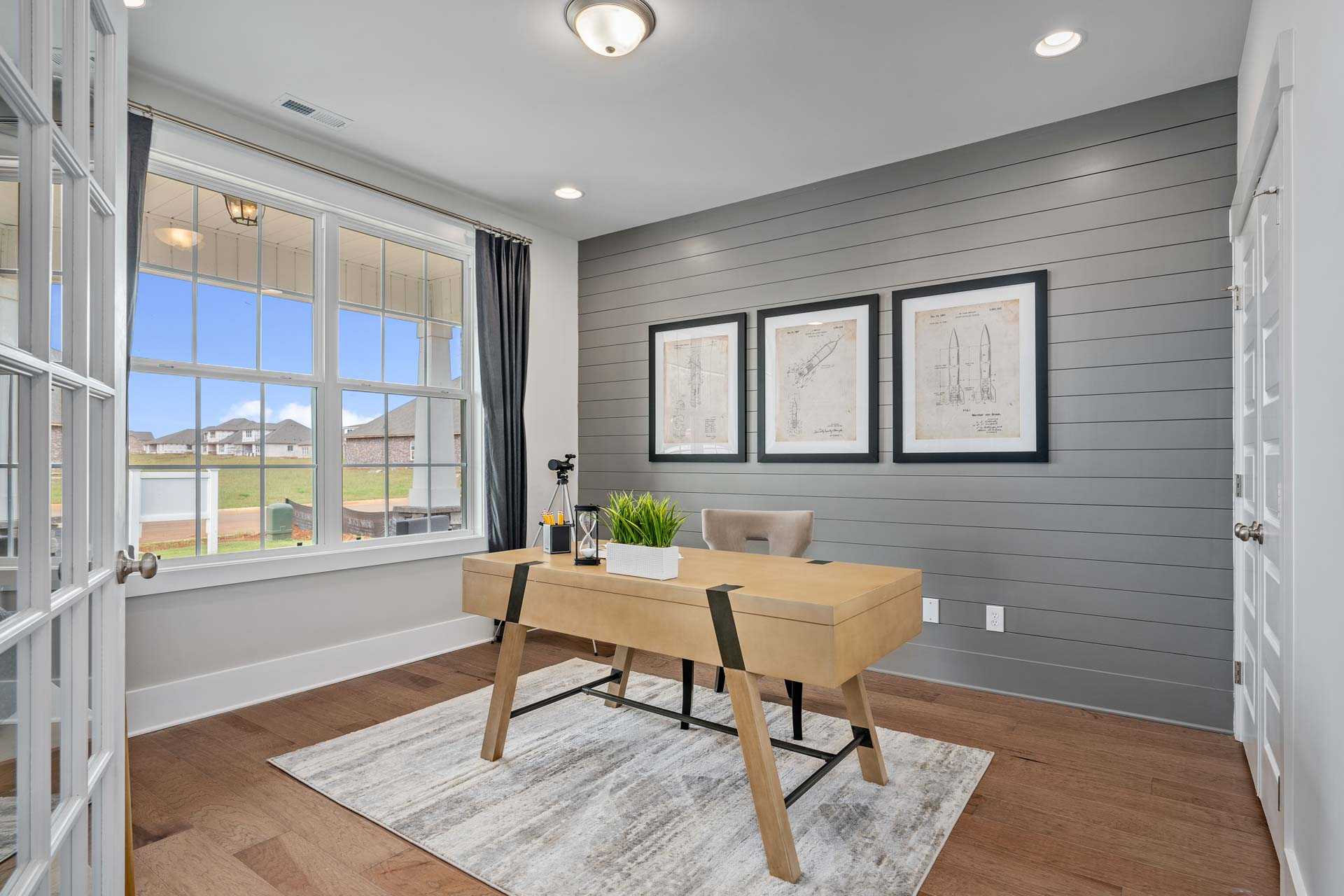 Modern home office in Kendall Downs Toney Alabama with wooden desk gray shiplap walls and large windows