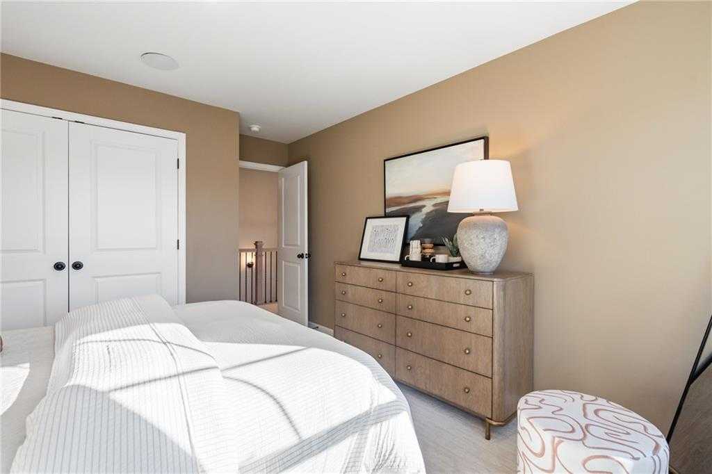 Elegant master bedroom with plush king bed, wooden dresser, abstract artwork, and walk-in closet in Davidson Homes The Marion C, Winder GA