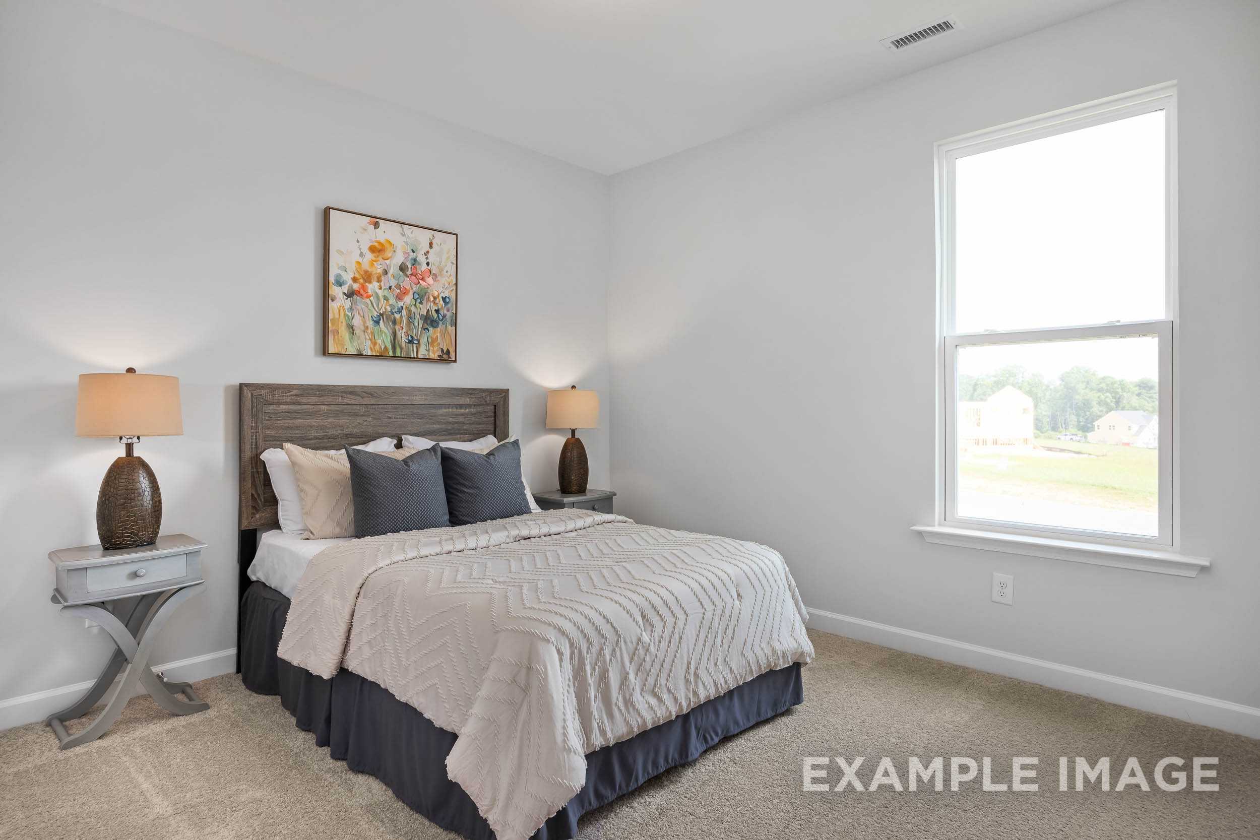 Cozy master bedroom in The Daphne C featuring queen bed with neutral bedding, wooden headboard, lamps, floral art, and large window