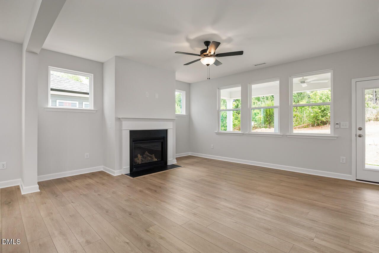 Bright living room with fireplace and wood-style flooring in The Birch II E floor plan at Sage on North Main, Wake Forest.