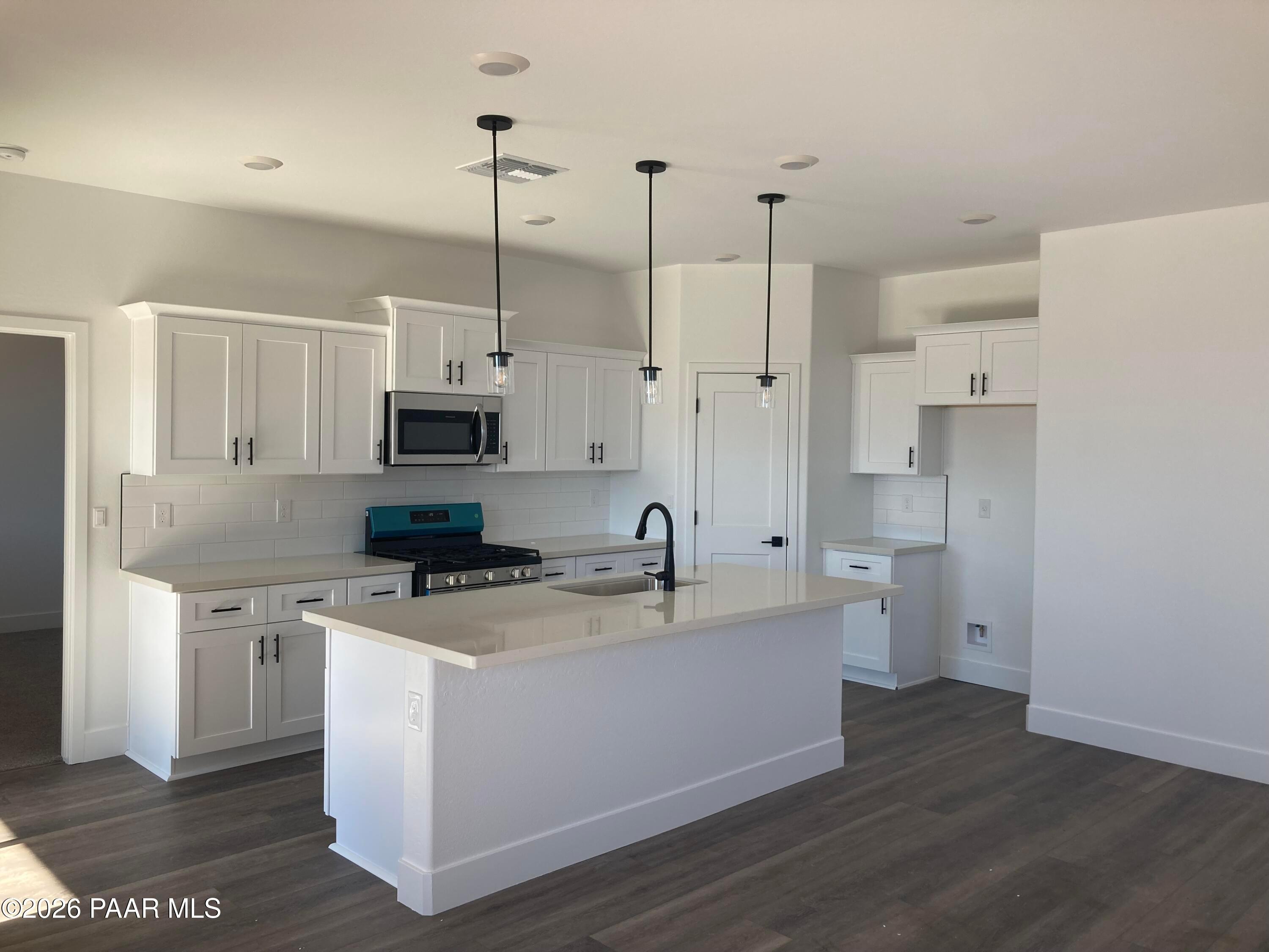 Bright open-concept kitchen with white shaker cabinets, large island sink, stainless appliances in Davidson Homes Malibu C, Prescott AZ