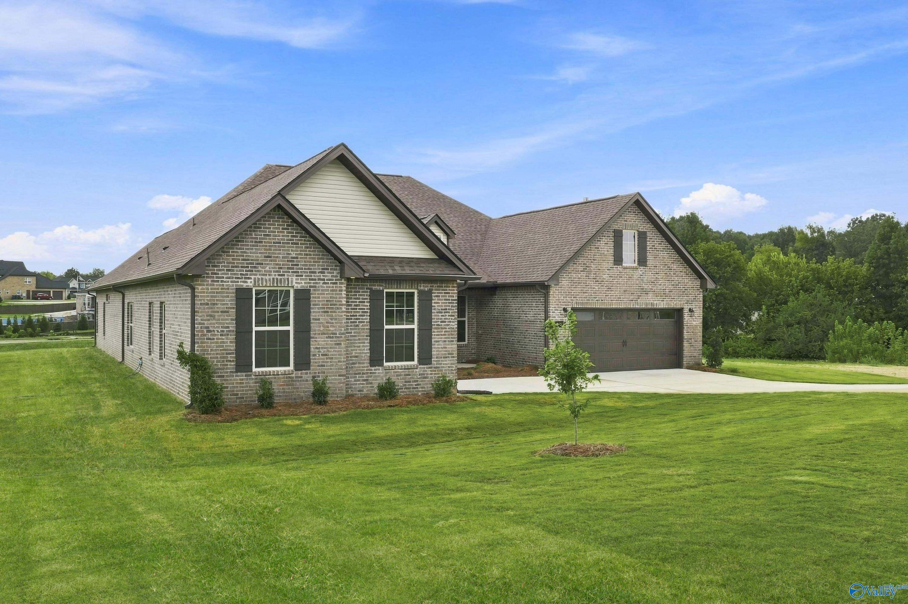 Brick 1-story home with 3-car garage and lush lawn at Riverton Preserve, Davidson Homes The Valencia, Huntsville, Alabama
