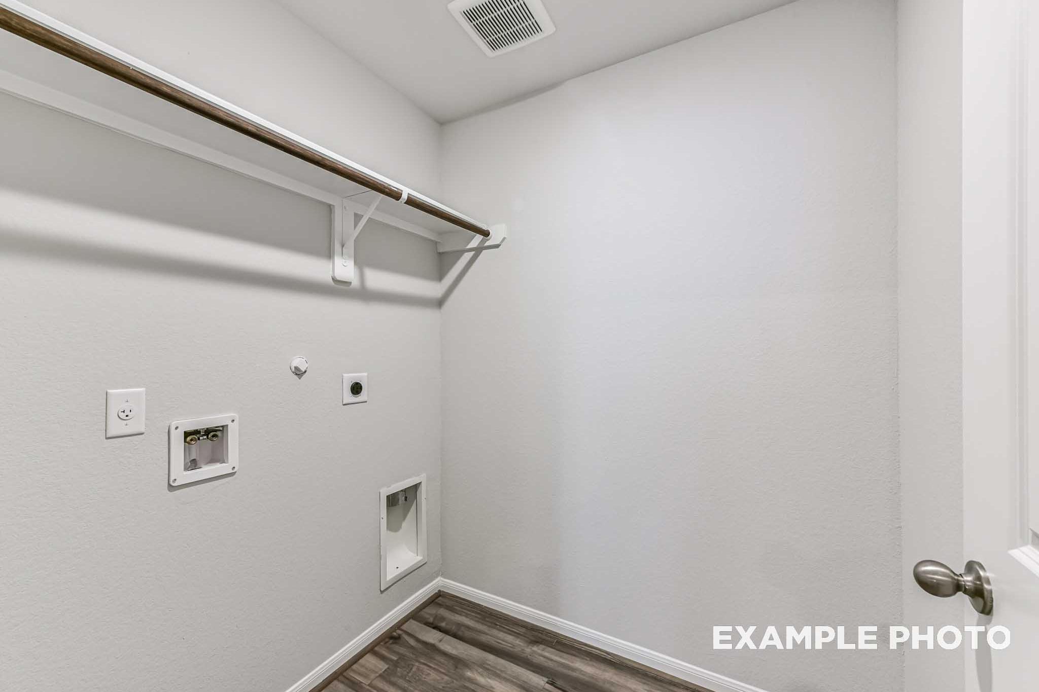 Laundry room in The Laguna A home featuring white walls, wooden hanging rod, utility sink hookups, dryer vent, and pet door