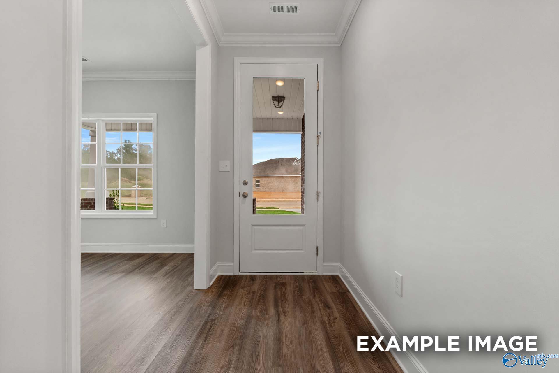 Bright hallway with open white door to covered porch overlooking green yard in Davidson Homes The Shelby C, Arab, Alabama