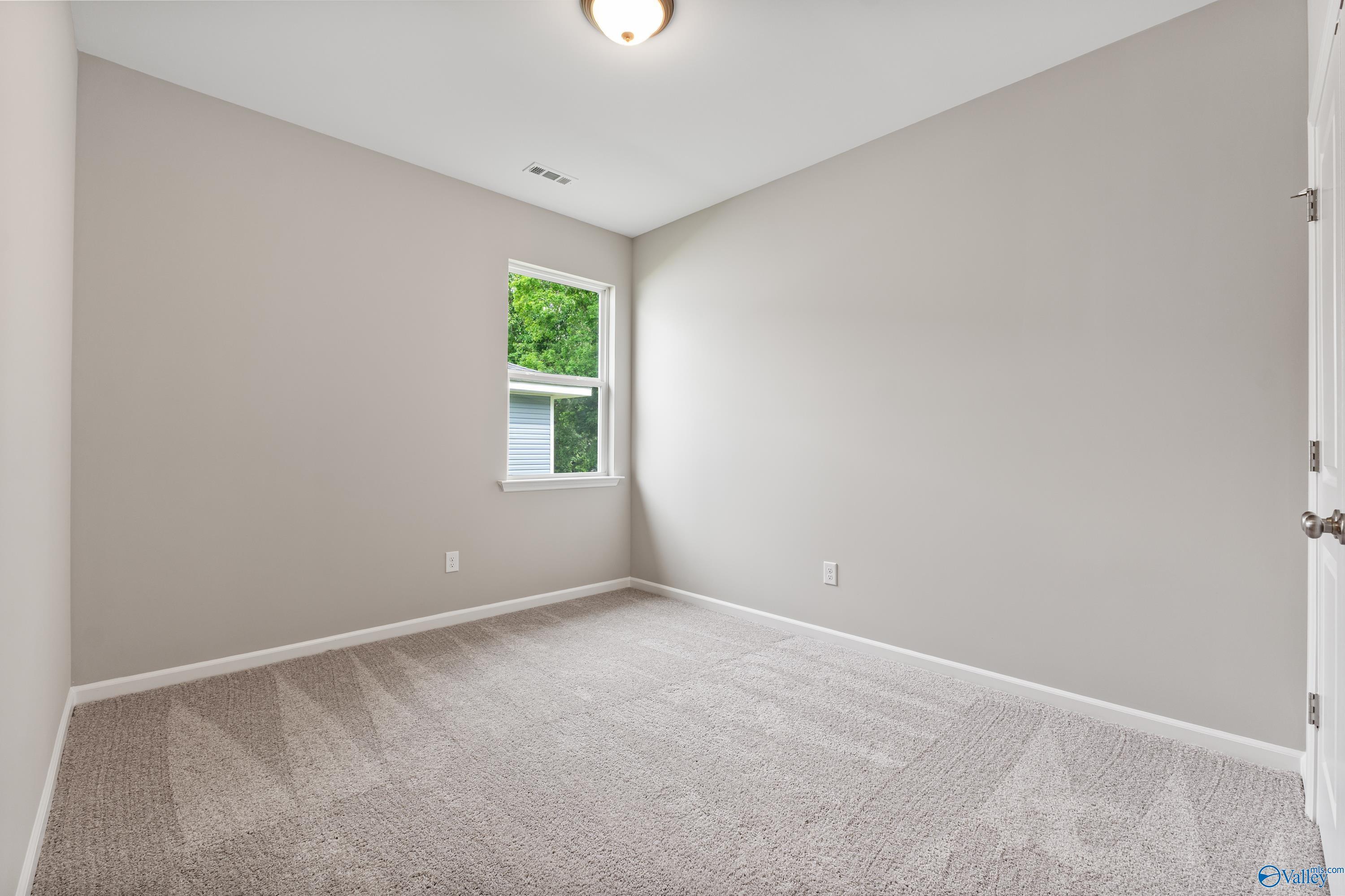 Bright secondary bedroom with gray walls, beige carpet, and tree-view window in The Aurora 4-bedroom home, Fayetteville, TN