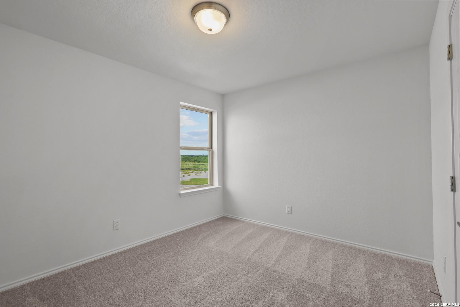 Bright, neutral bedroom with plush carpeting in The Brazos B floor plan at Davidson Homes in Agave, San Antonio, Texas.